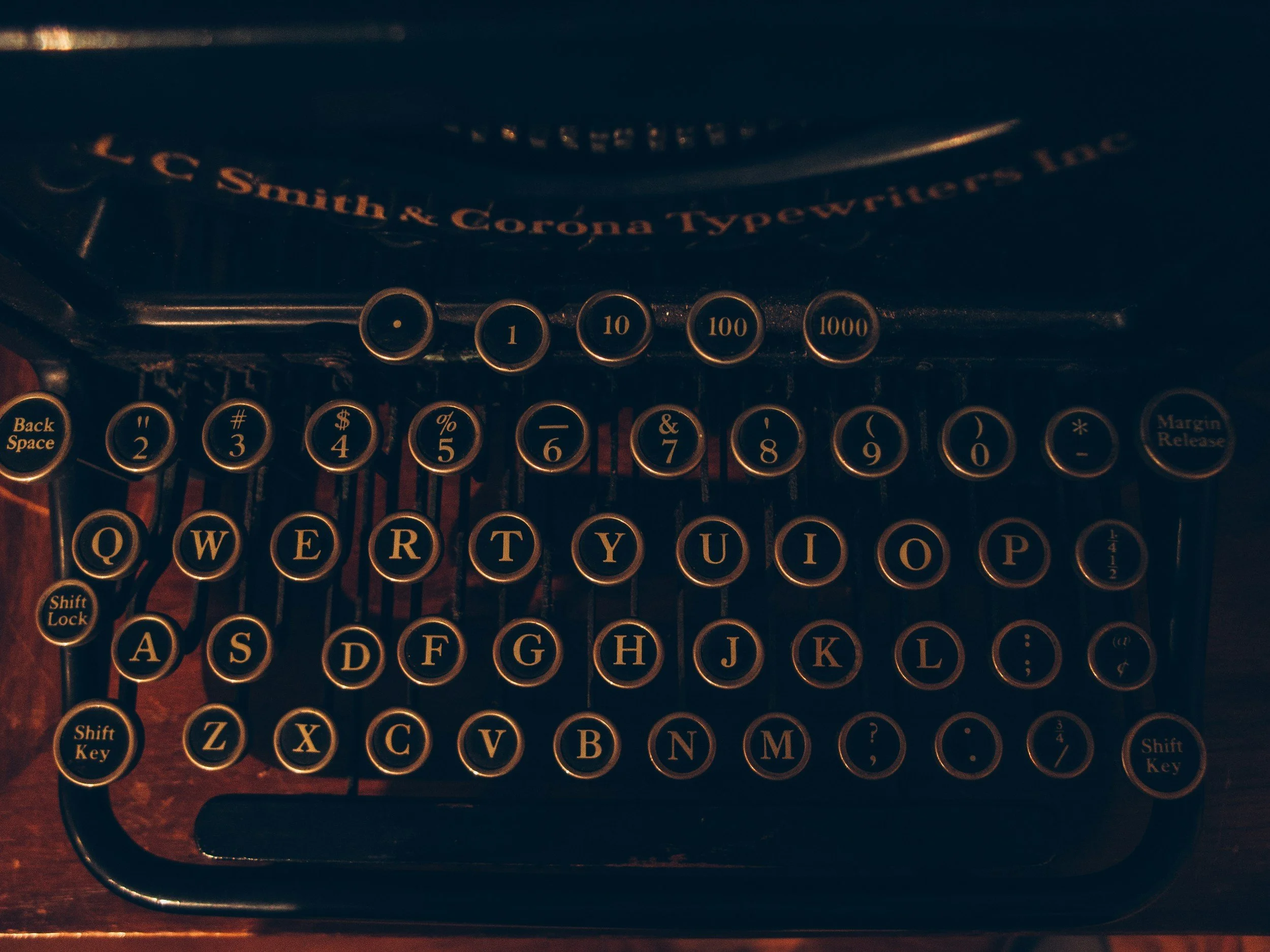 Close-up of a vintage black typewriter with round keys and yellow lettering.