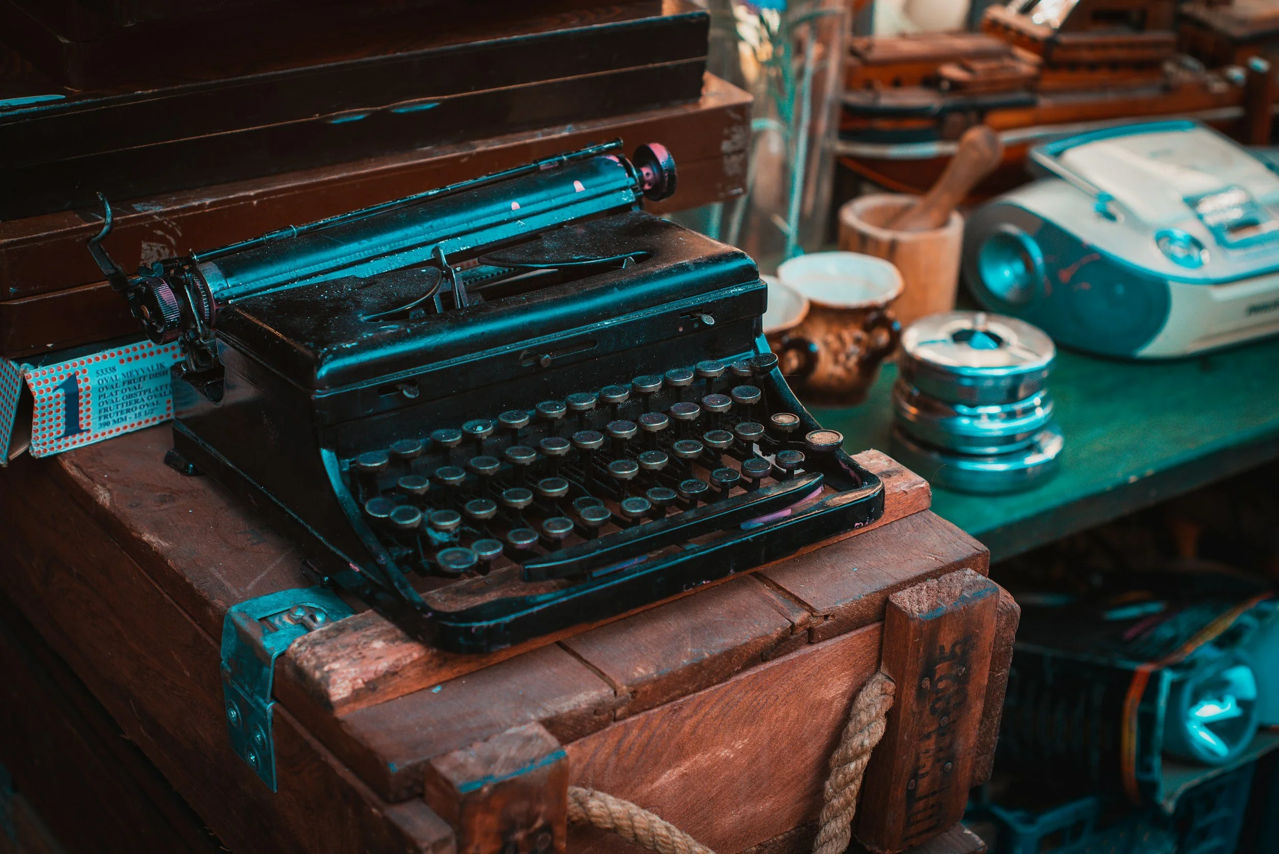 Vintage black typewriter on a wooden table, surrounded by other retro items and equipment.