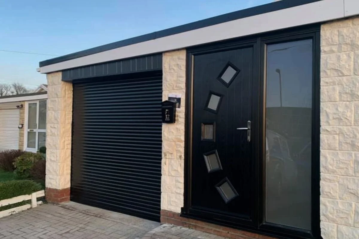 A single roller shutter door next to a front door, both in a modern black colour. 
