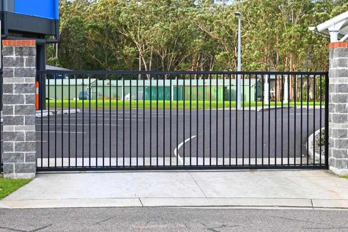Black sliding gates infront of a car park.