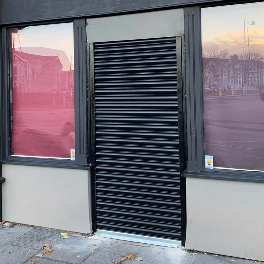 Cafe front protected by a single black roller shutter, fully closed.