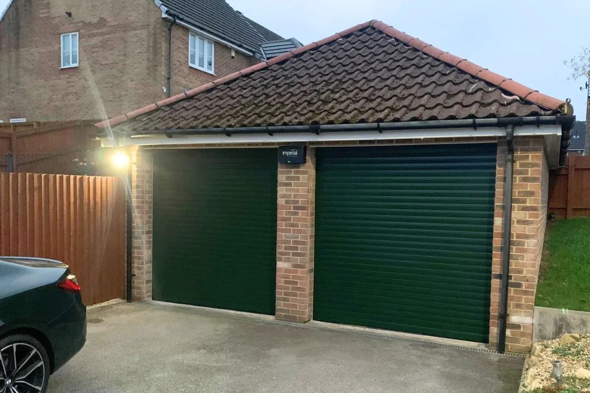 Two roller shutter garage doors beside each other on a brick building, in a modern green colour.