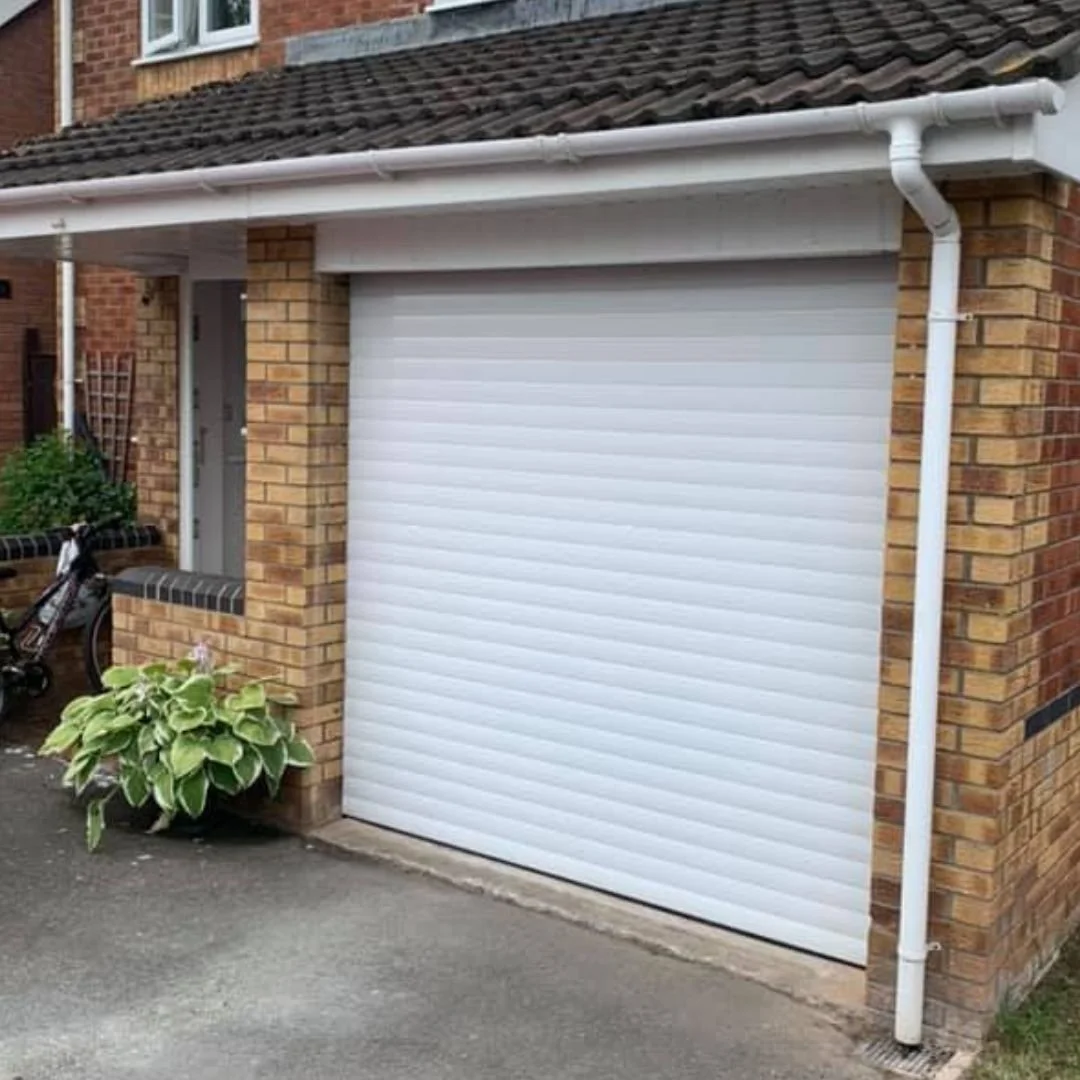 A white roller shutter door closed against a residential brick property.