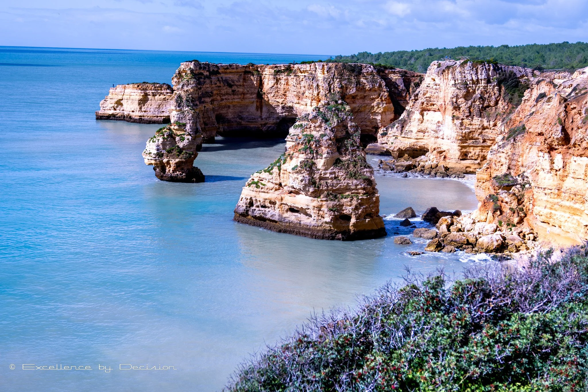 Rocky coastal cliffs with sea arches overlooking blue ocean waters.