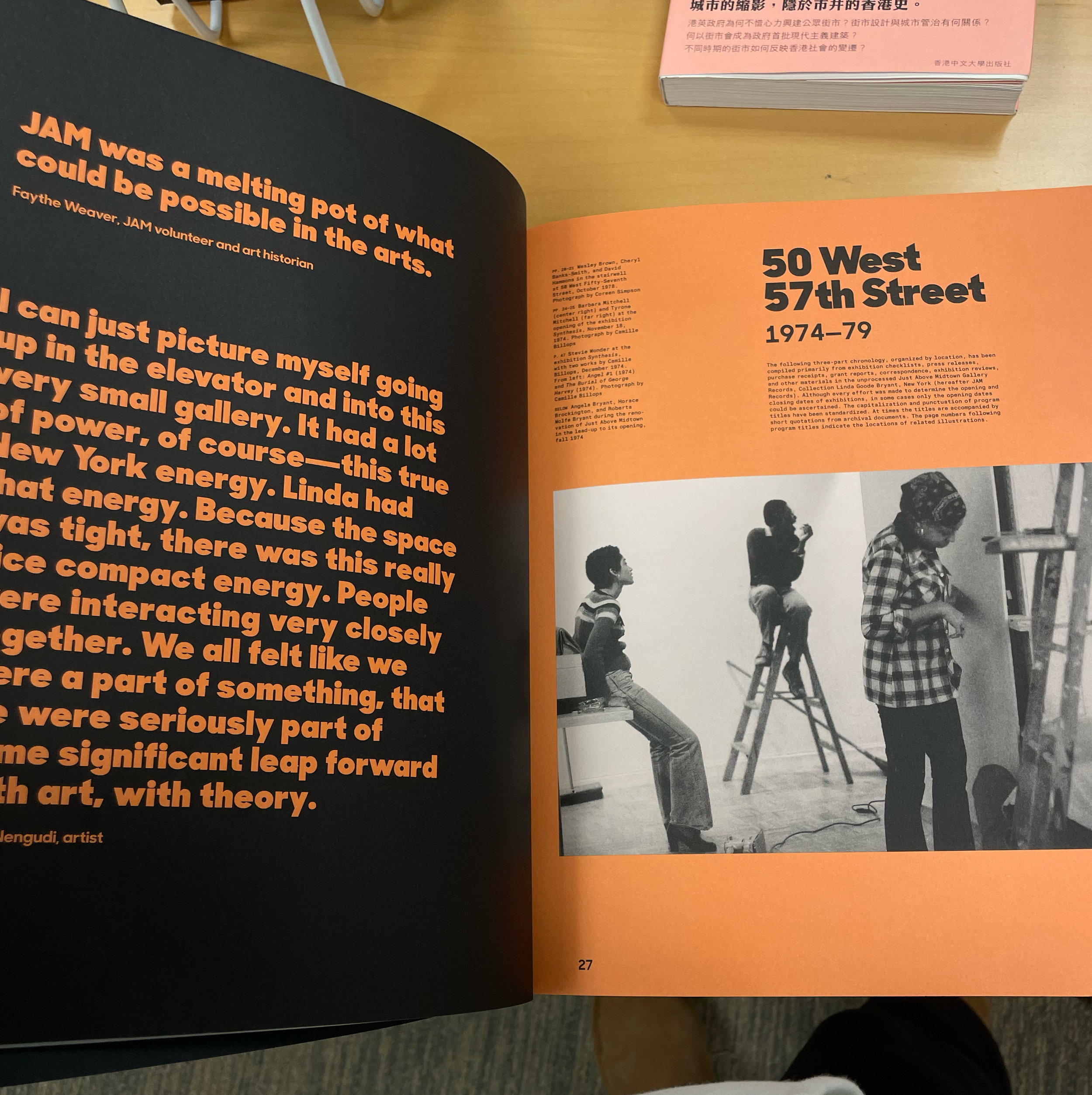 Page from a book with orange and black background. The right side features the title '50 West 57th Street 1974-79' with a black and white photo of three women in an art studio, one sitting on a wall, one on a ladder, and one standing.