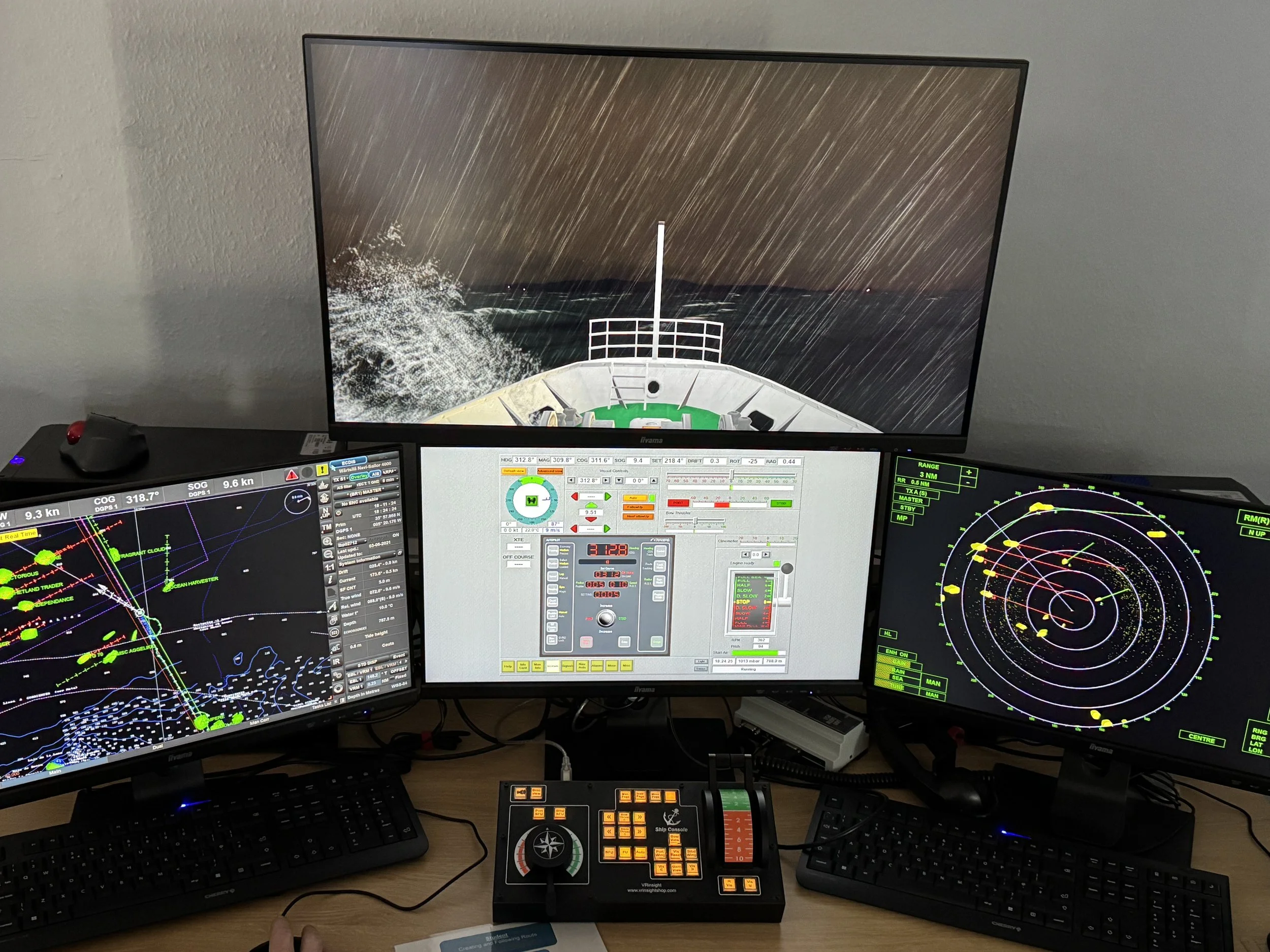 The You & Sea Transas simulator showing the three monitors displaying navigation, radar, and weather data for maritime navigation, with a control panel and keyboards, and a large screen above to show the view from the ship's deck.