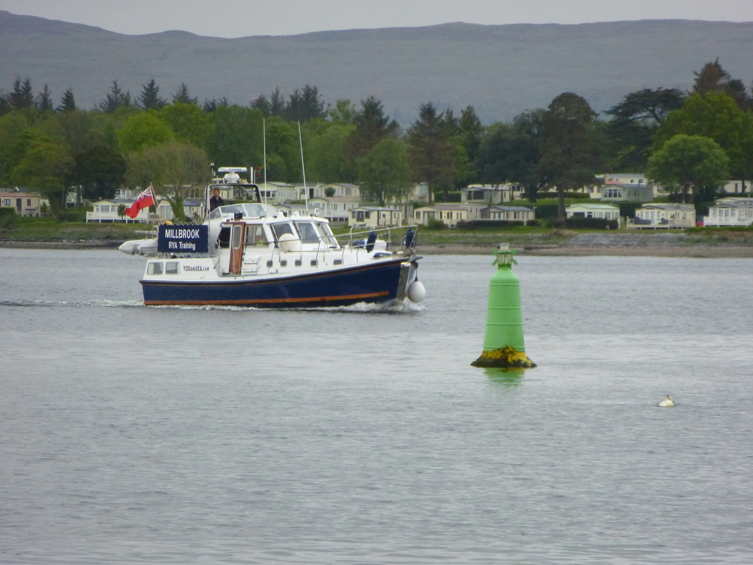 A boat passing a single green starboard marker in a channel
