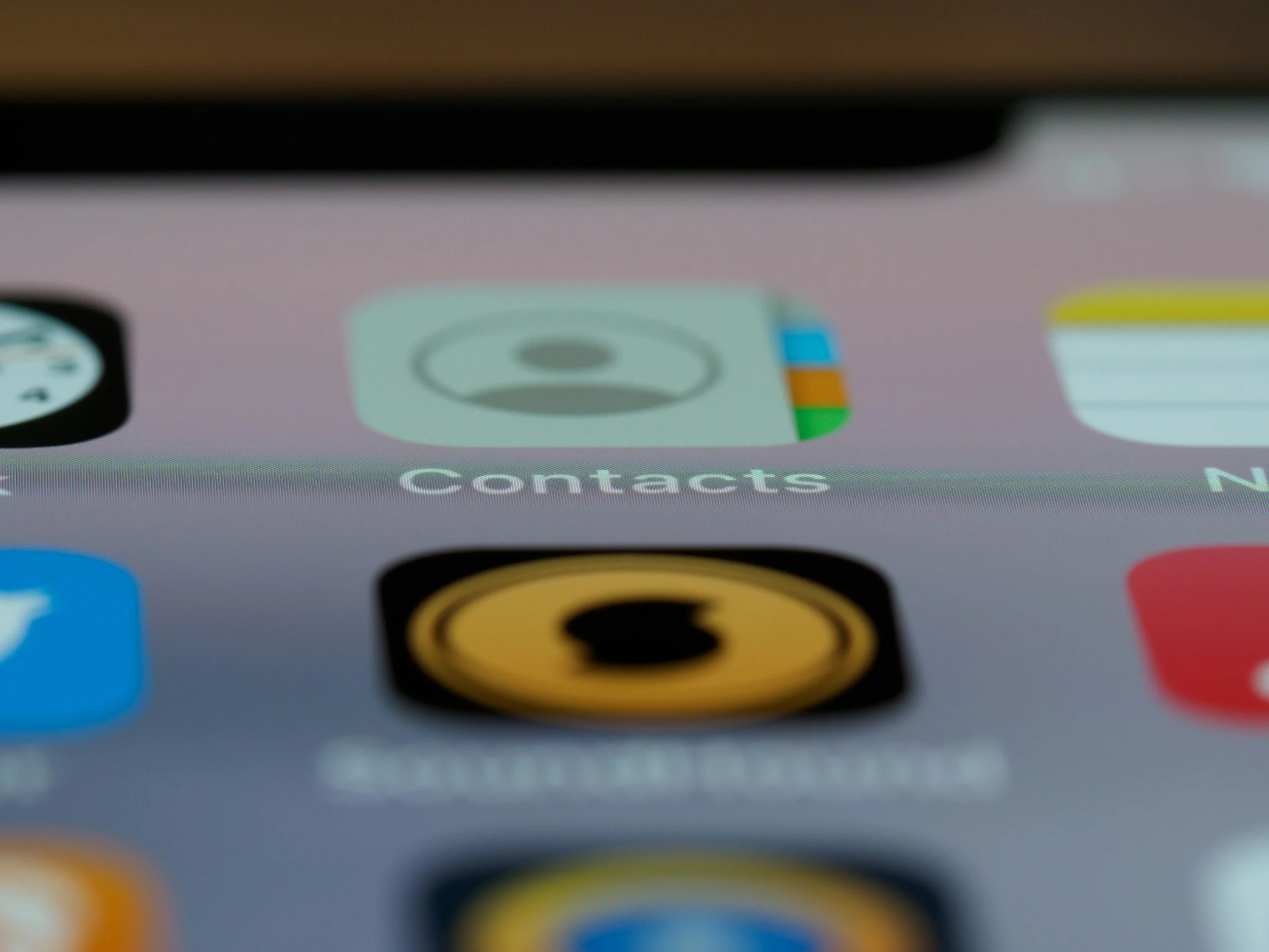 Close-up of a mobile phone screen showing a contacts app icon, with other app icons partially visible around it.
