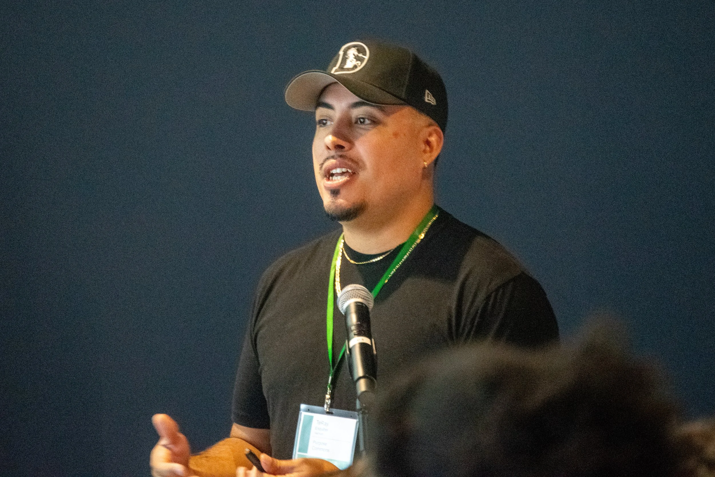 A man stands at a dias with a microphone giving a lecture.