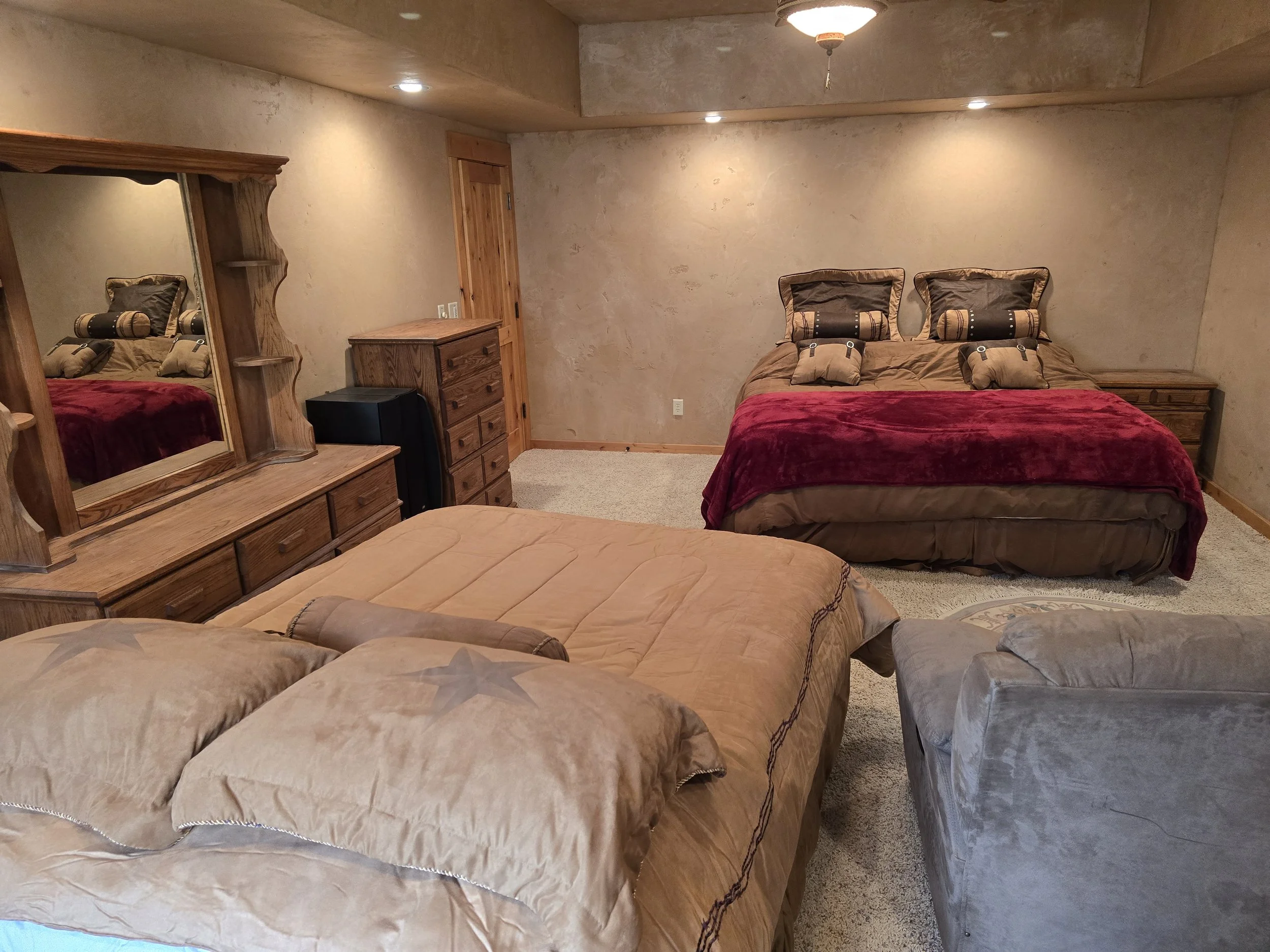 Cozy bedroom with two beds, wooden dresser, mirror, and neutral decor.