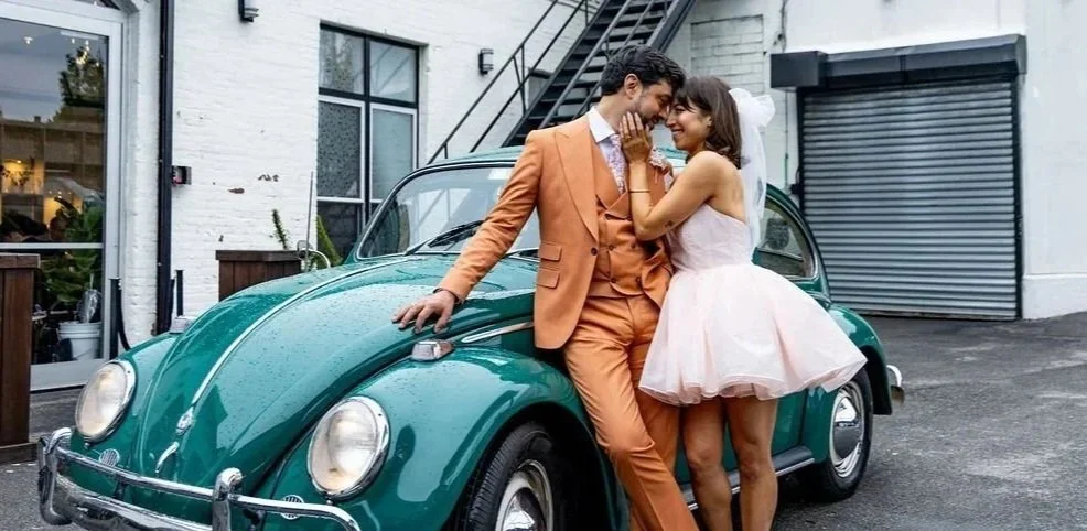 Newlyweds stepping into a vintage car after their ceremony outside the venue.
