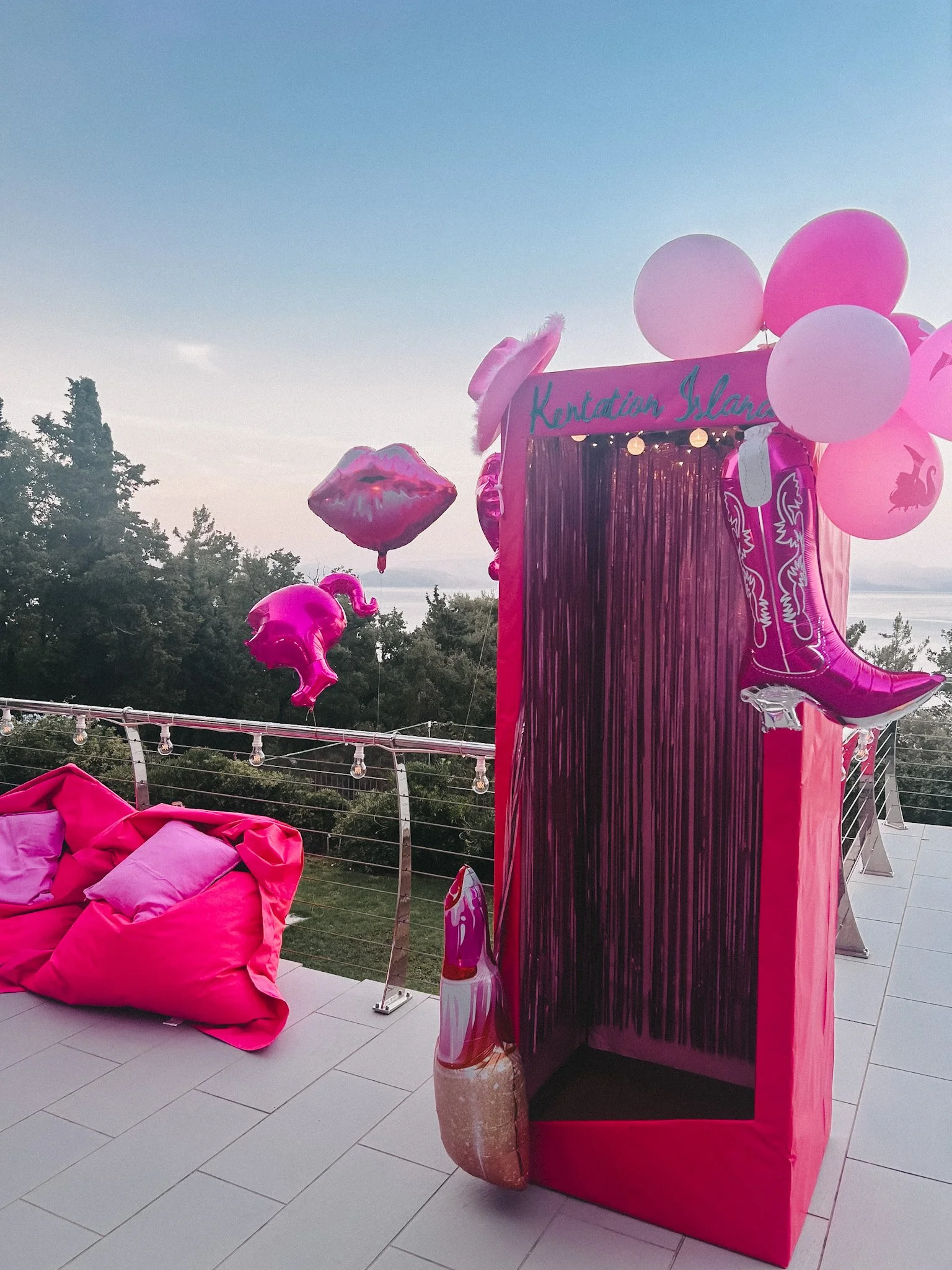 Blaue Himmel, pinke Luftballons, pinke Deko, Wasser im Hintergrund, Beleuchtung, gepolsterte pinke Sitzbank