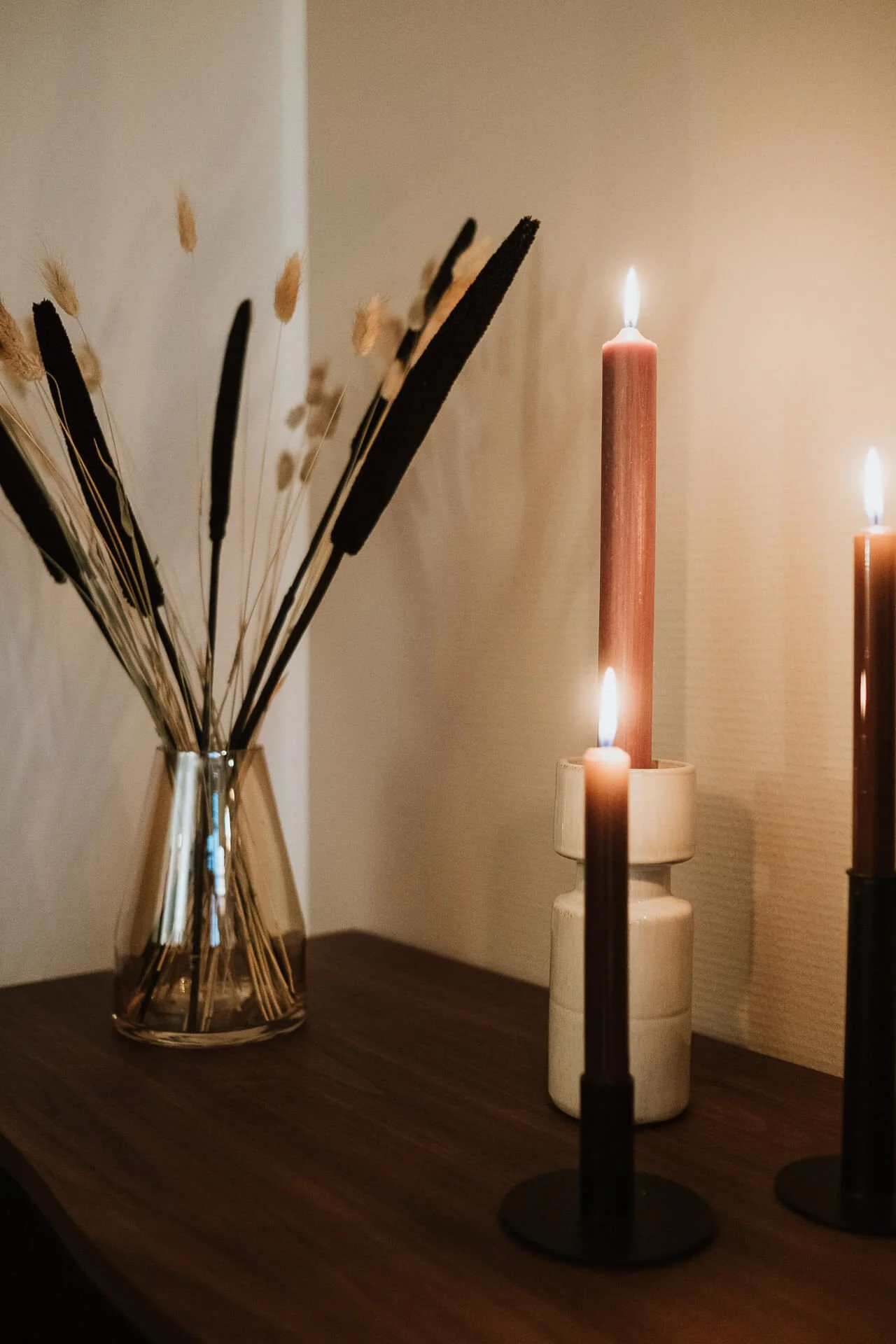 Vasen mit getrockneten Gräsern und Kerzen auf einem Holz Tisch, warmes Licht