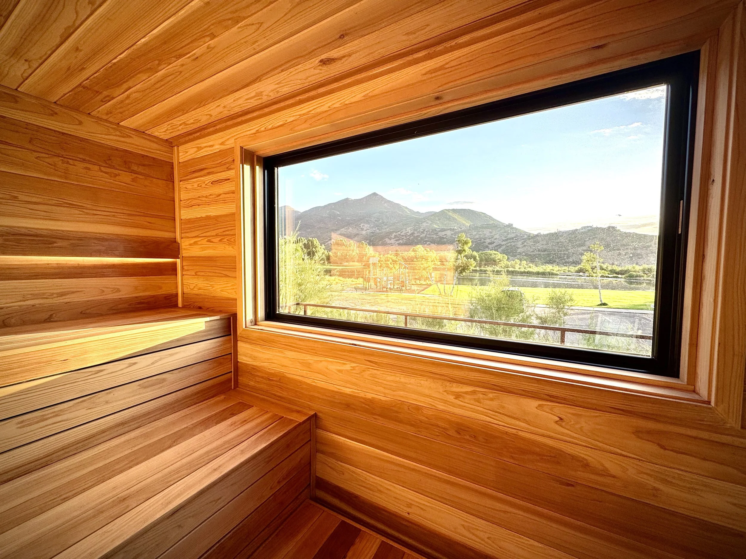 Wood-paneled interior with a large window showcasing a mountain landscape with trees and a clear sky.