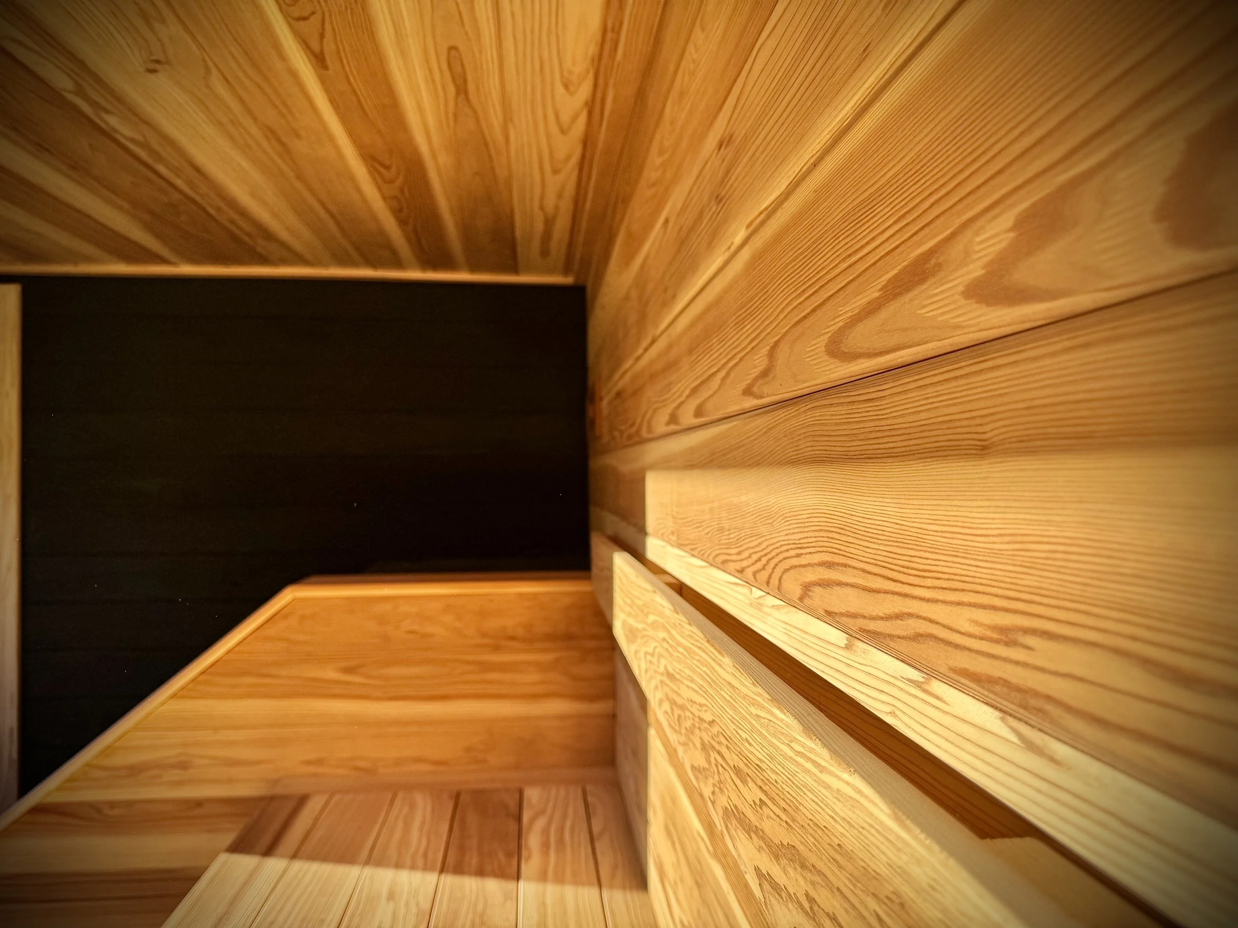 Close-up view of wooden stairs and wall in a room, with an angle showing the wood grain and texture.