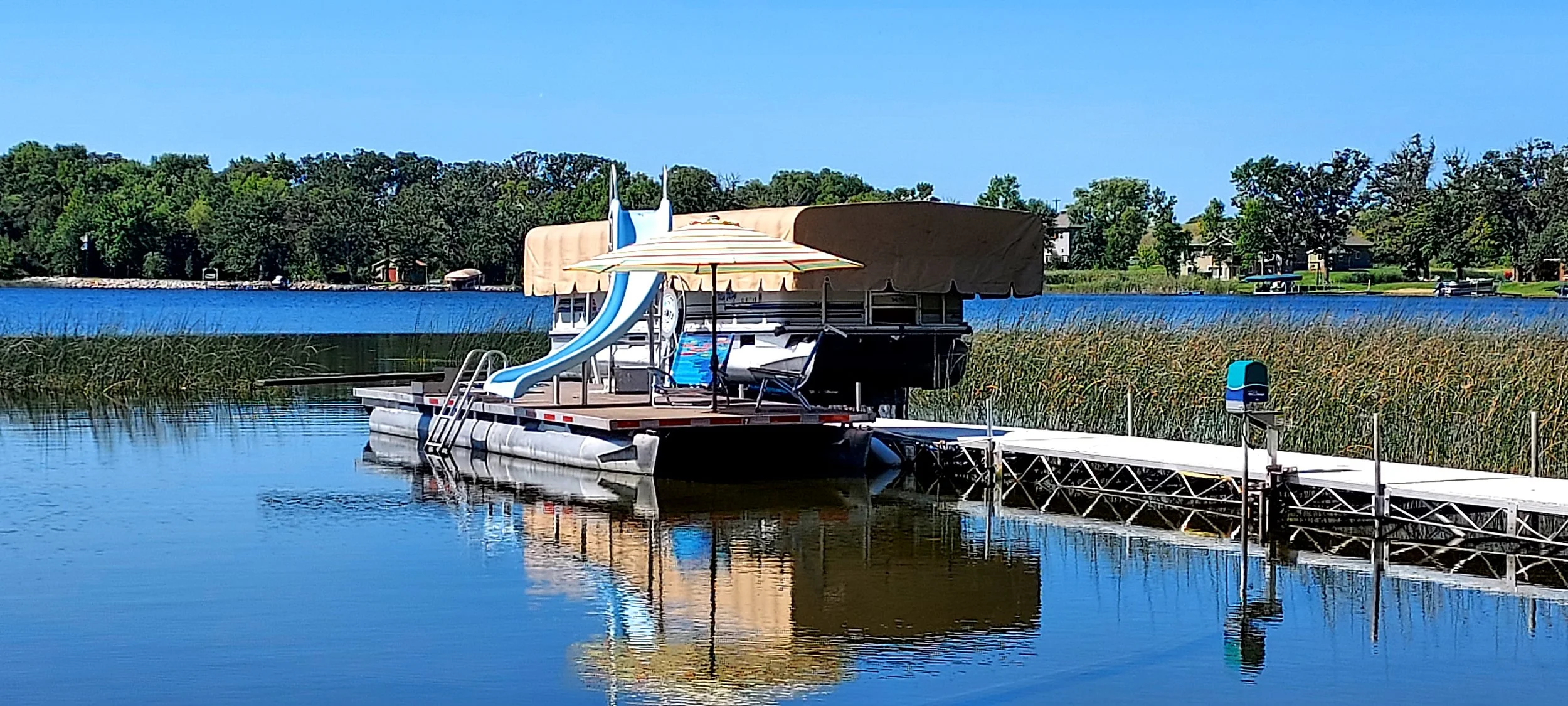 View of the dock with the water slide, and the pontoon (available to rent) on Little Chippewa Lake.