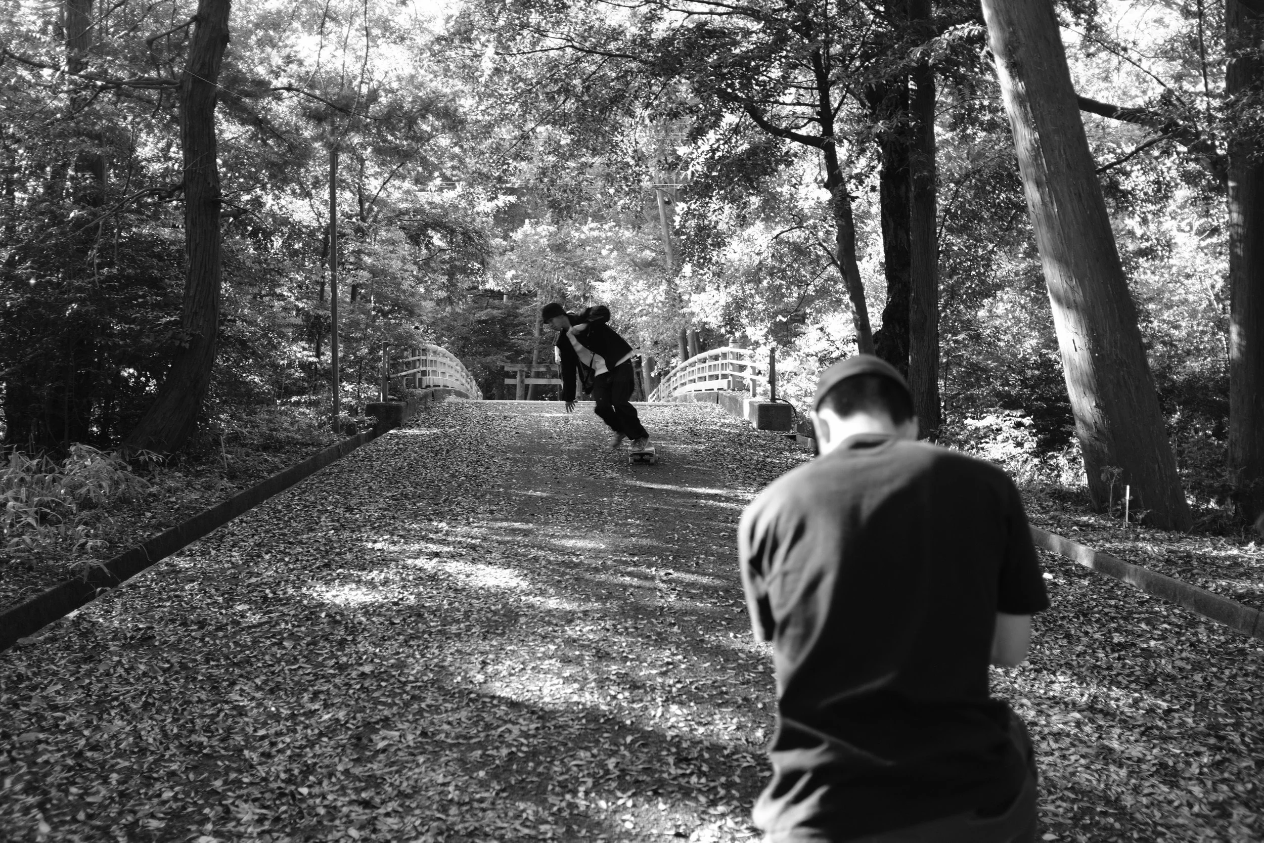 A black and white photo of the street photographer, Takeshi Hayakawa of Street Dreams Magazine Tokyo photographing a young skateboarder skating in the rural tea farming town of Wazuka, Kyoto