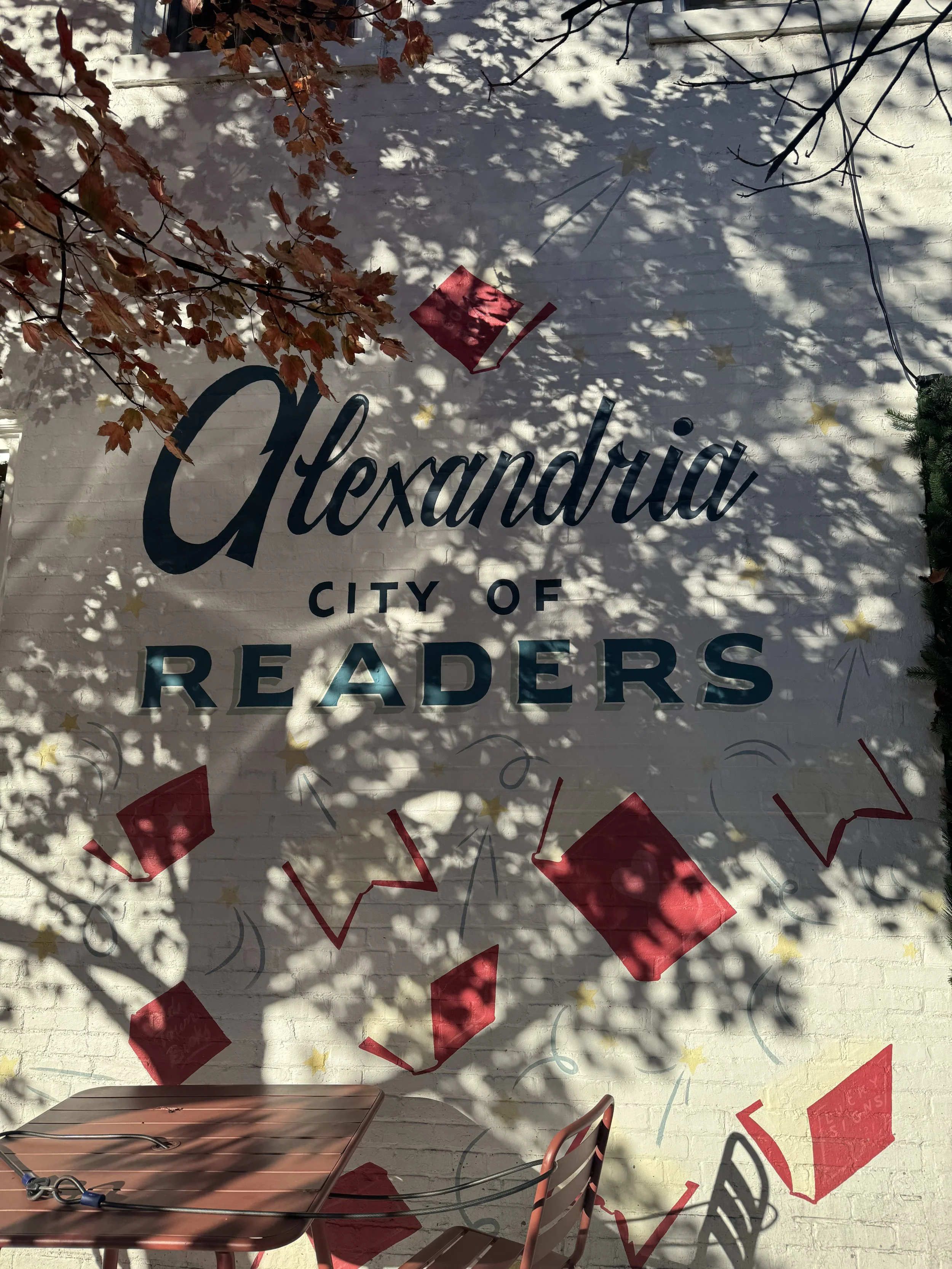 A mural that says "Alexandria City of Readers" in teal with red books painted around it.