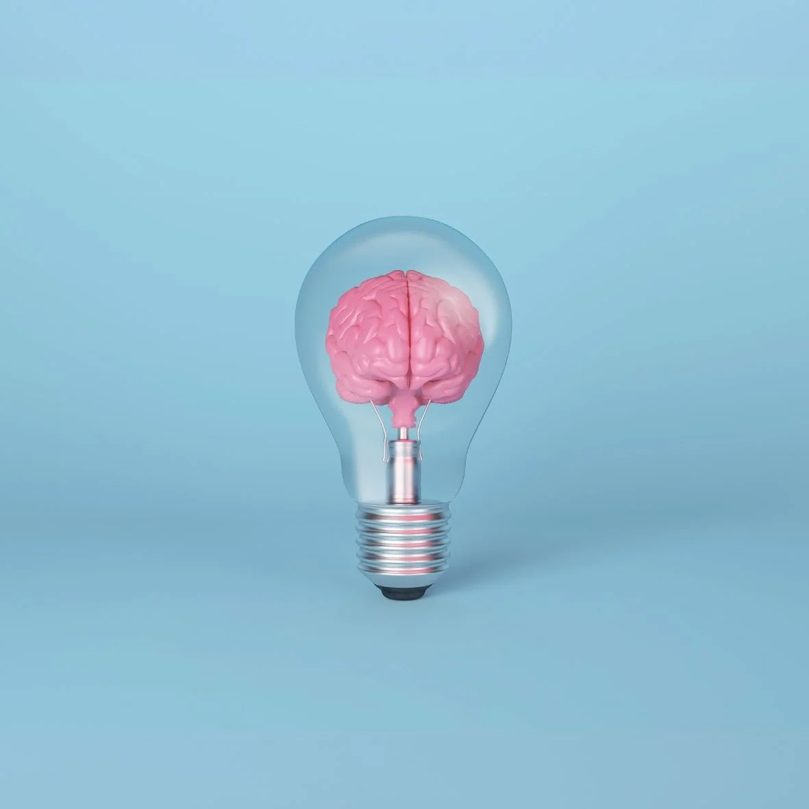 Photo of a lightbulb against a blue background, with a pink brain inside the lightbulb.