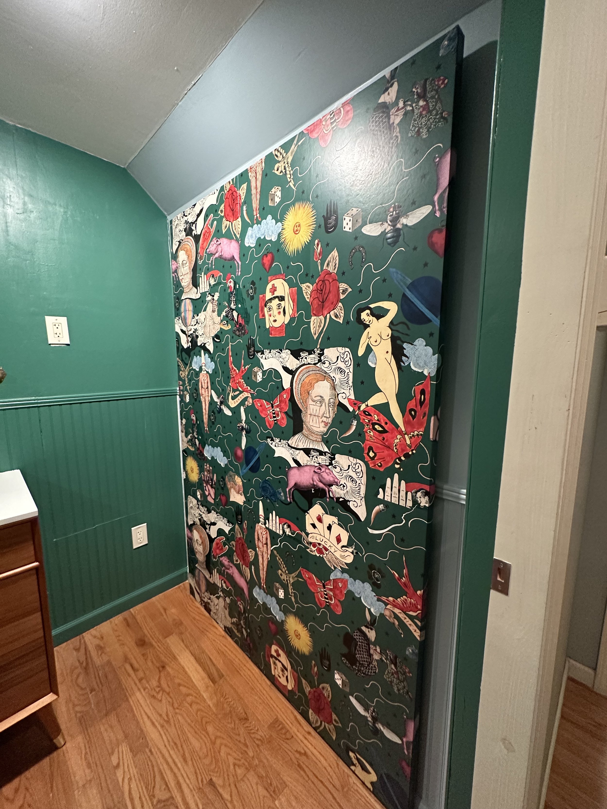 Decorated door with a colorful collage of various illustrations including a woman, a butterfly, a rat, playing cards, and other eclectic images.