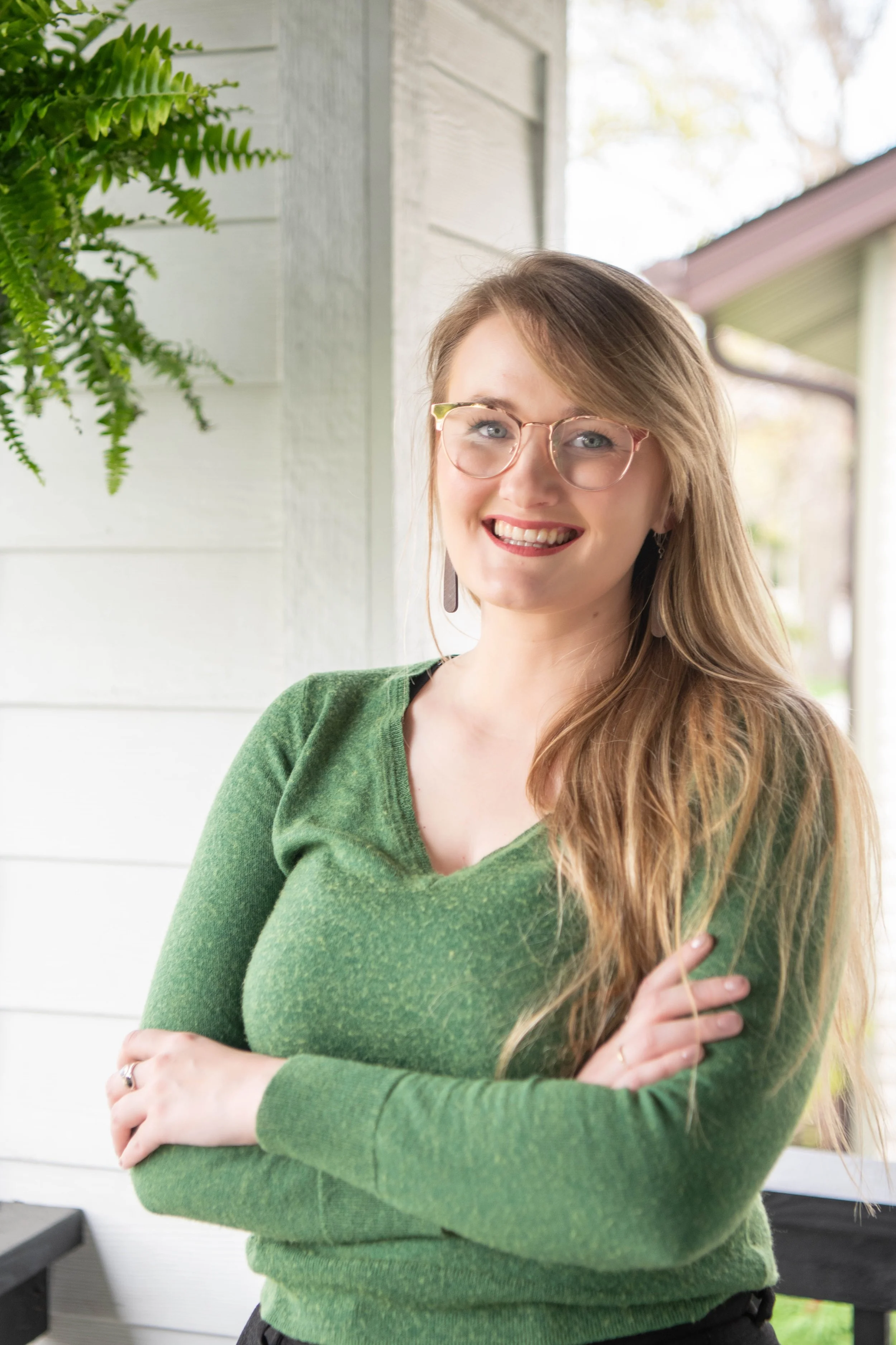Elisabeth Larson, Certified Nurse Midwife, with arms crossed below chest and smiling wide, wearing sage green sweather