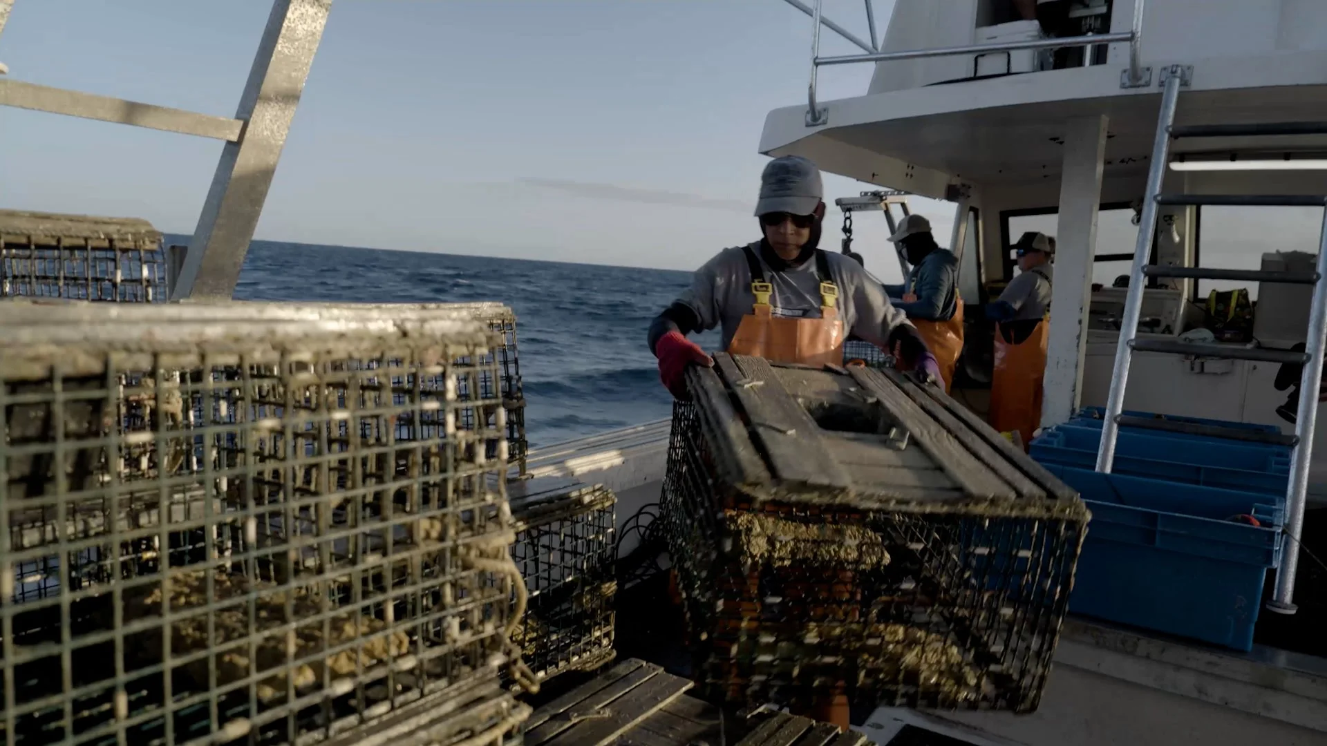 Fishermen loading lobster traps on a boat at sea.