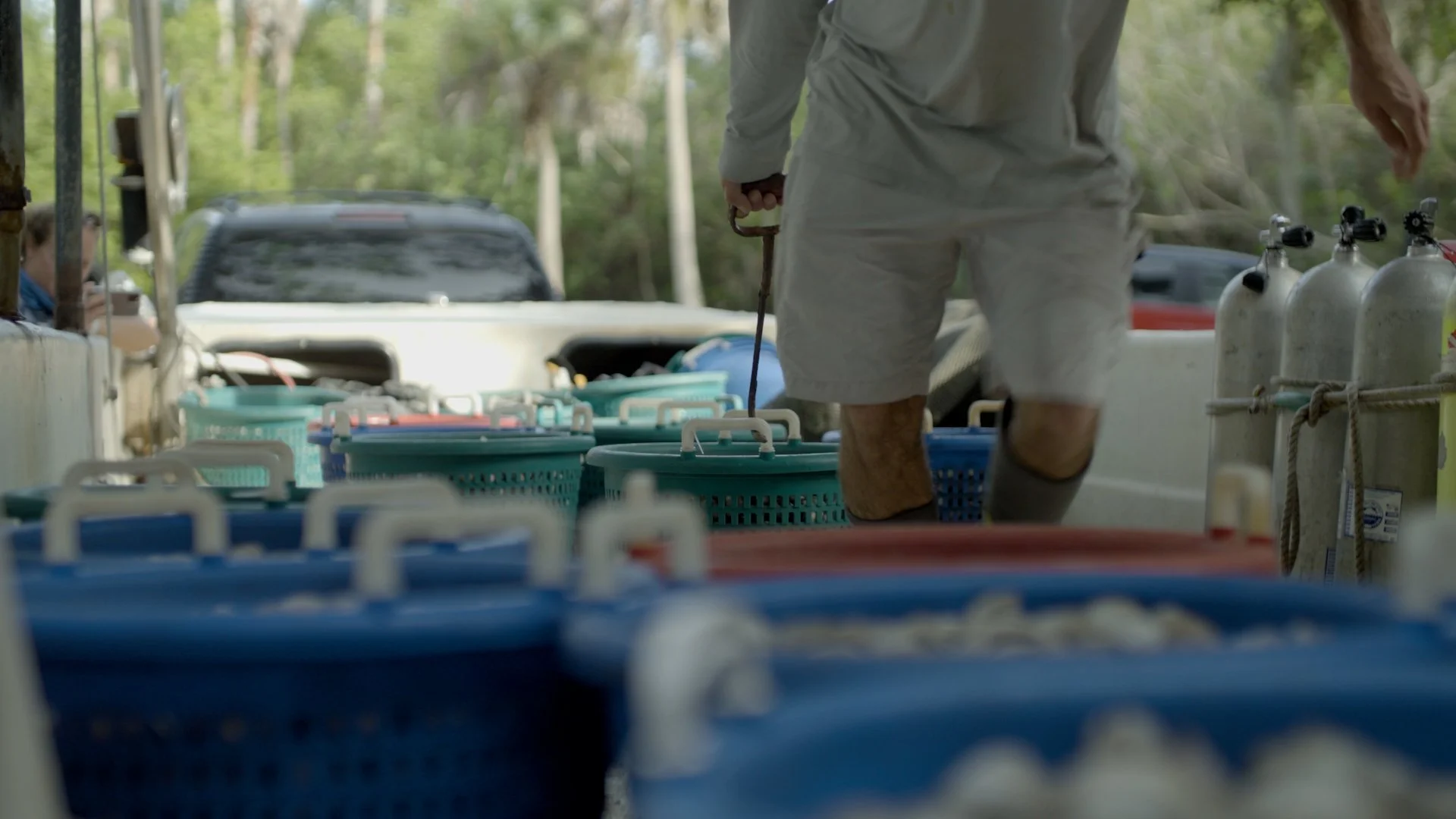 Person walking among blue baskets and gas cylinders on a boat