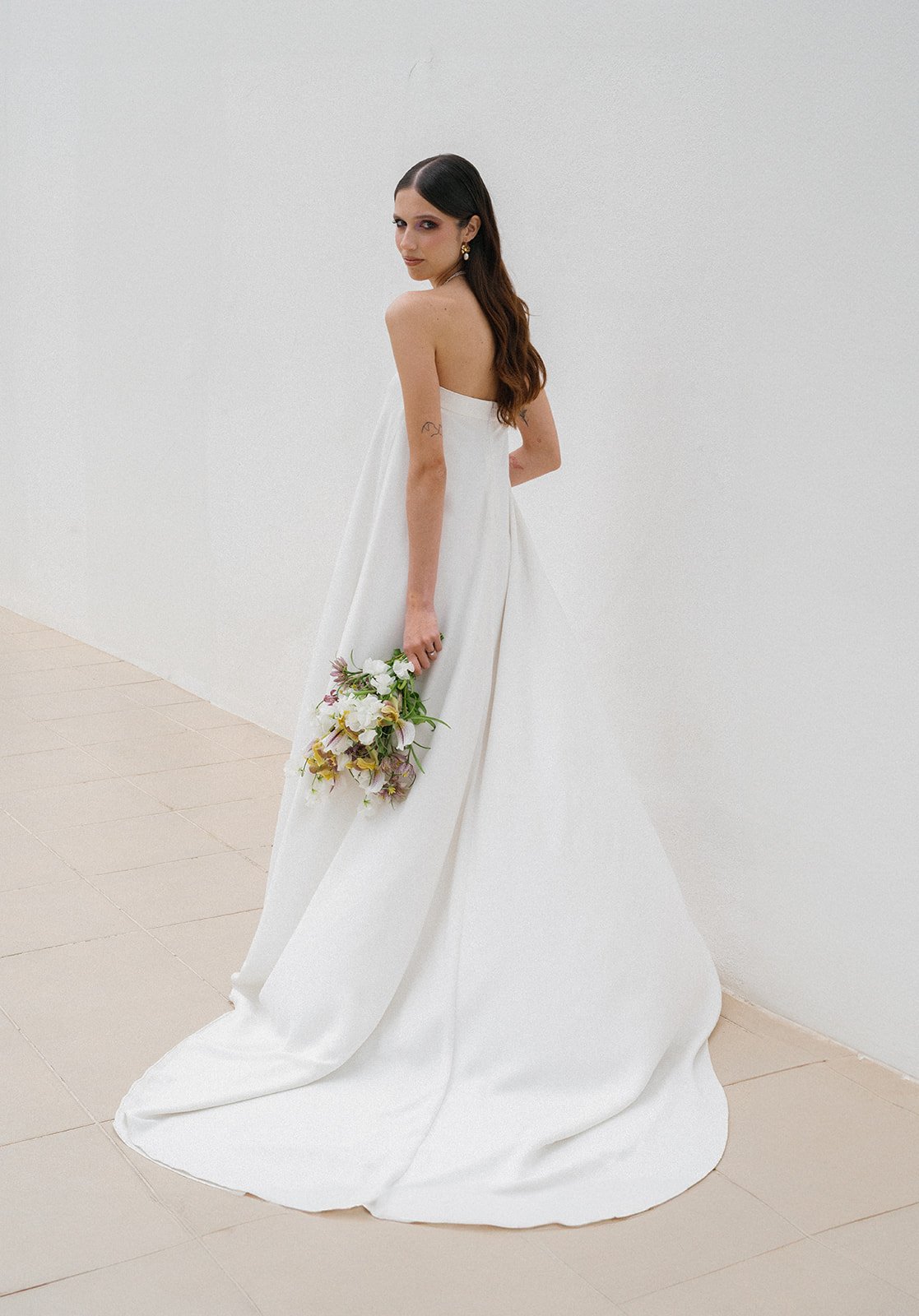 Modern bride from back, no veil, engaging eye contact, Portugal wedding.