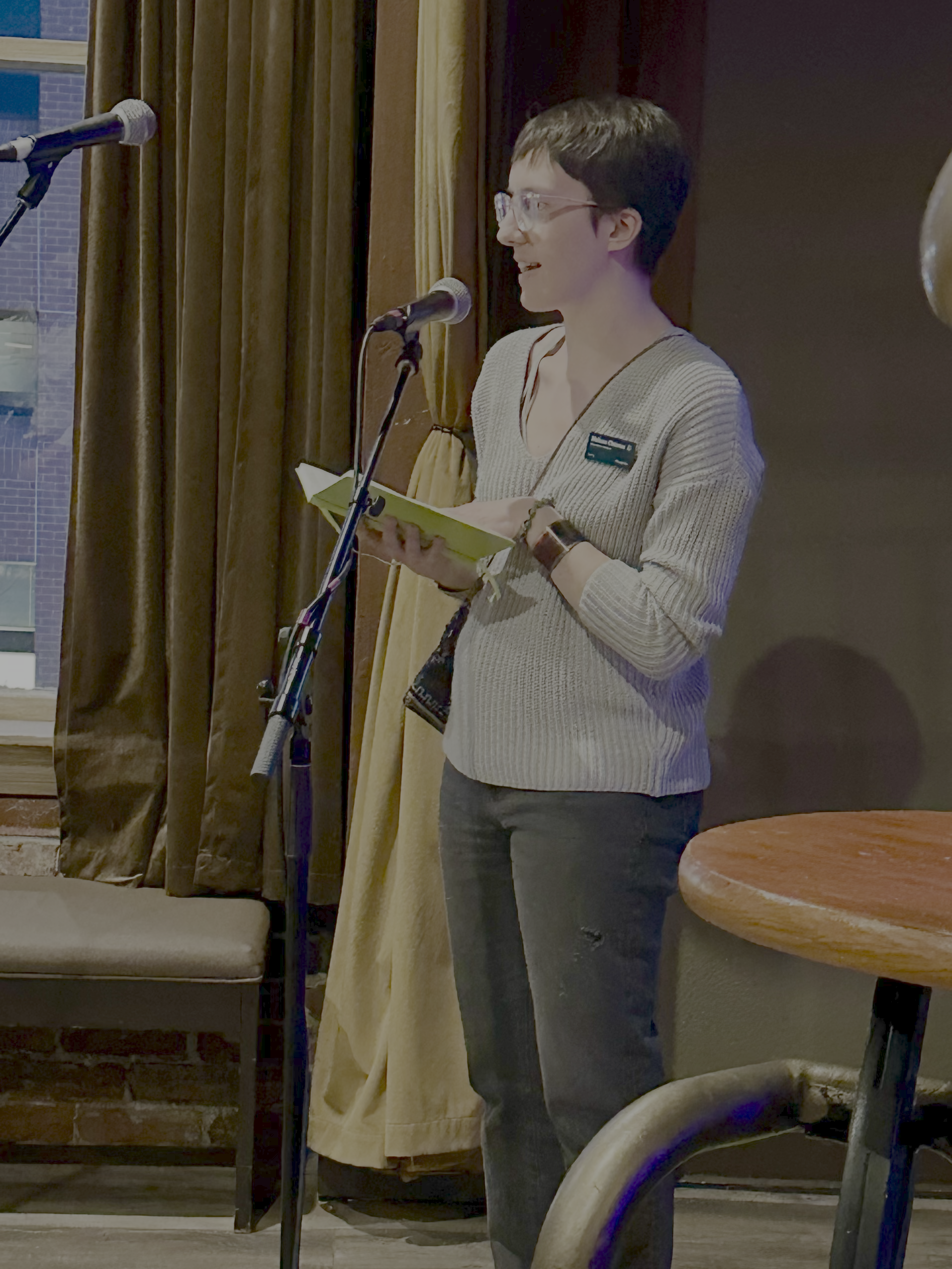  ChangeLine Health Equity Manager, Melissa Chizmar, speaks into a microphone while holding a notebook. 