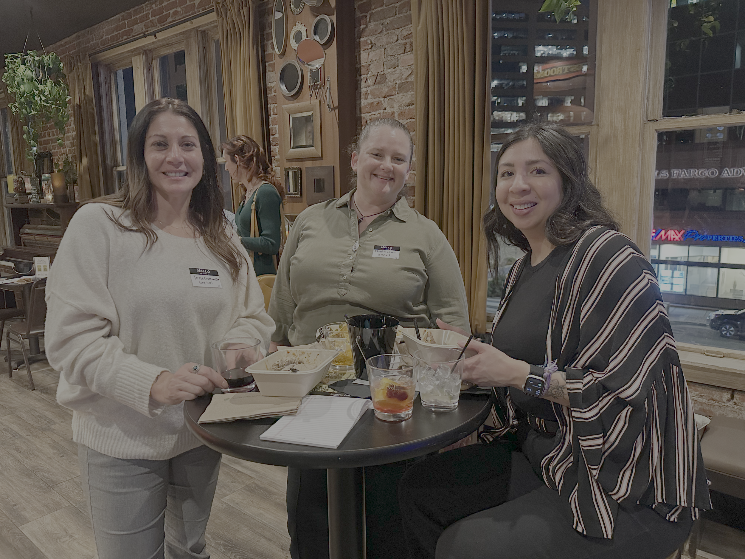  A group of three people around a small table smile for the camera. 