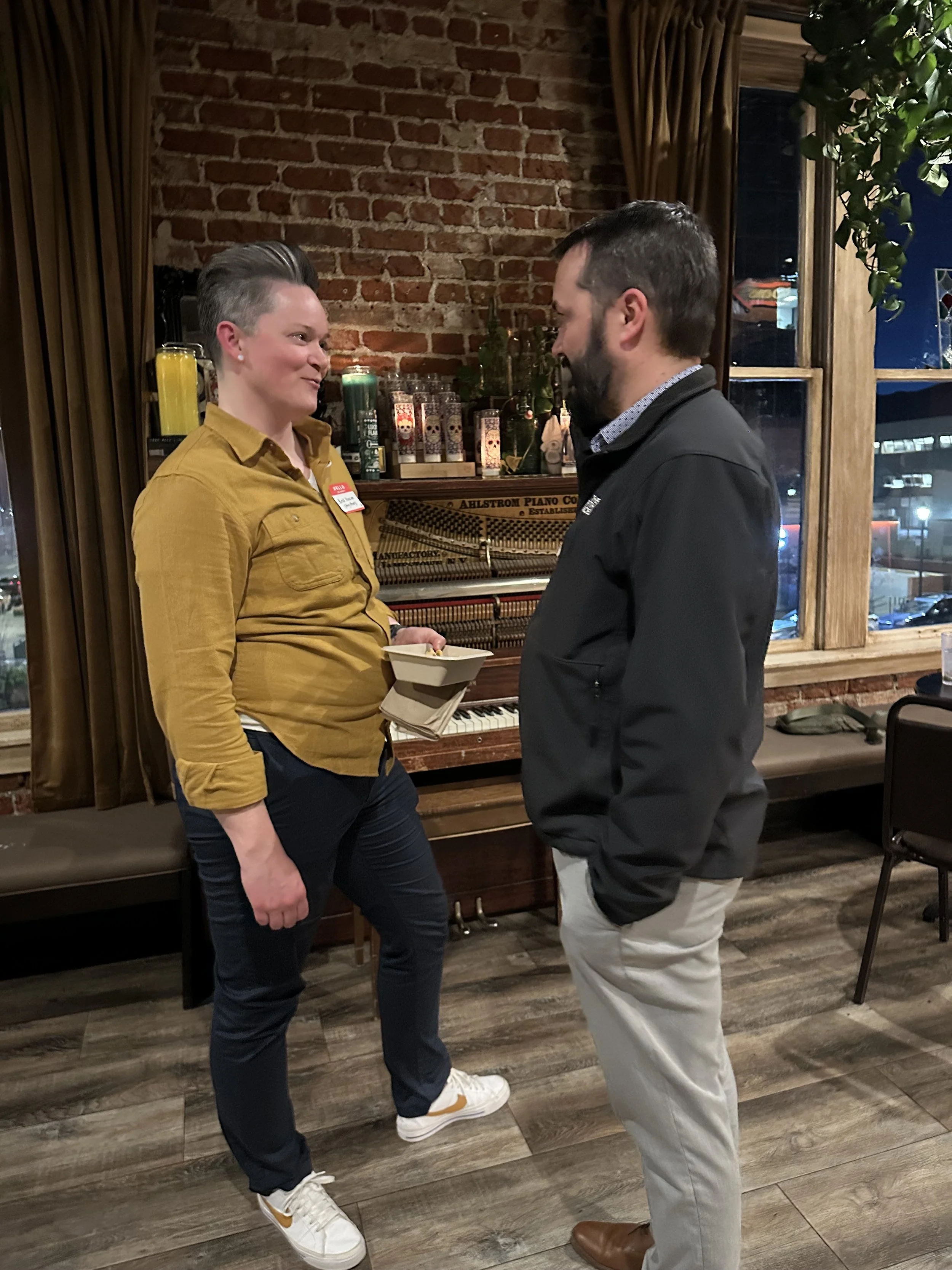  ChangeLine board member Colt Corman speaks with an attendee while standing casually near a brick wall. 
