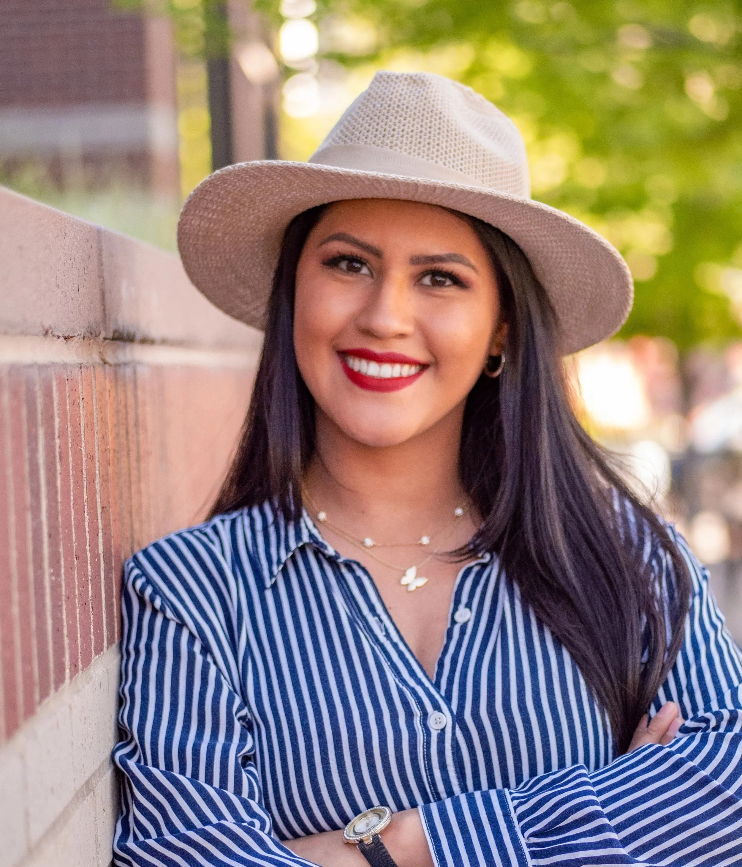 A smiling woman with long brown hair, white hat, and red lipstick