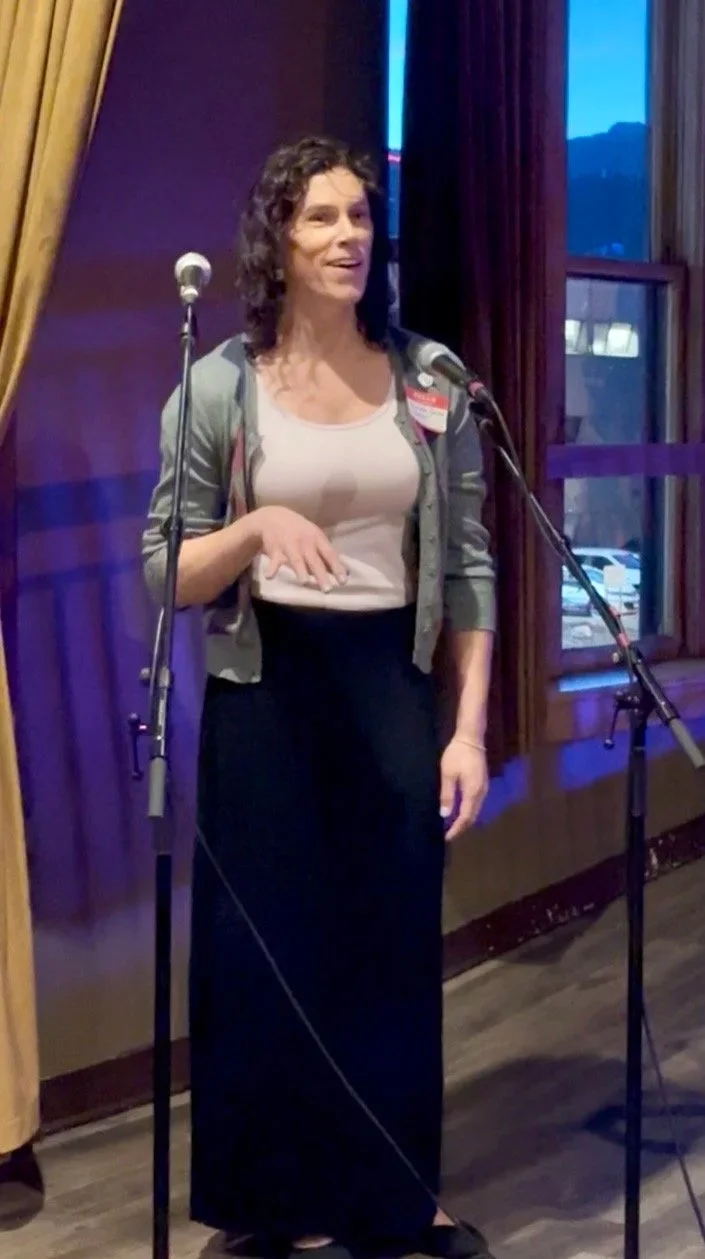 Close up of Charlotte standing behind a microphone and grinning.