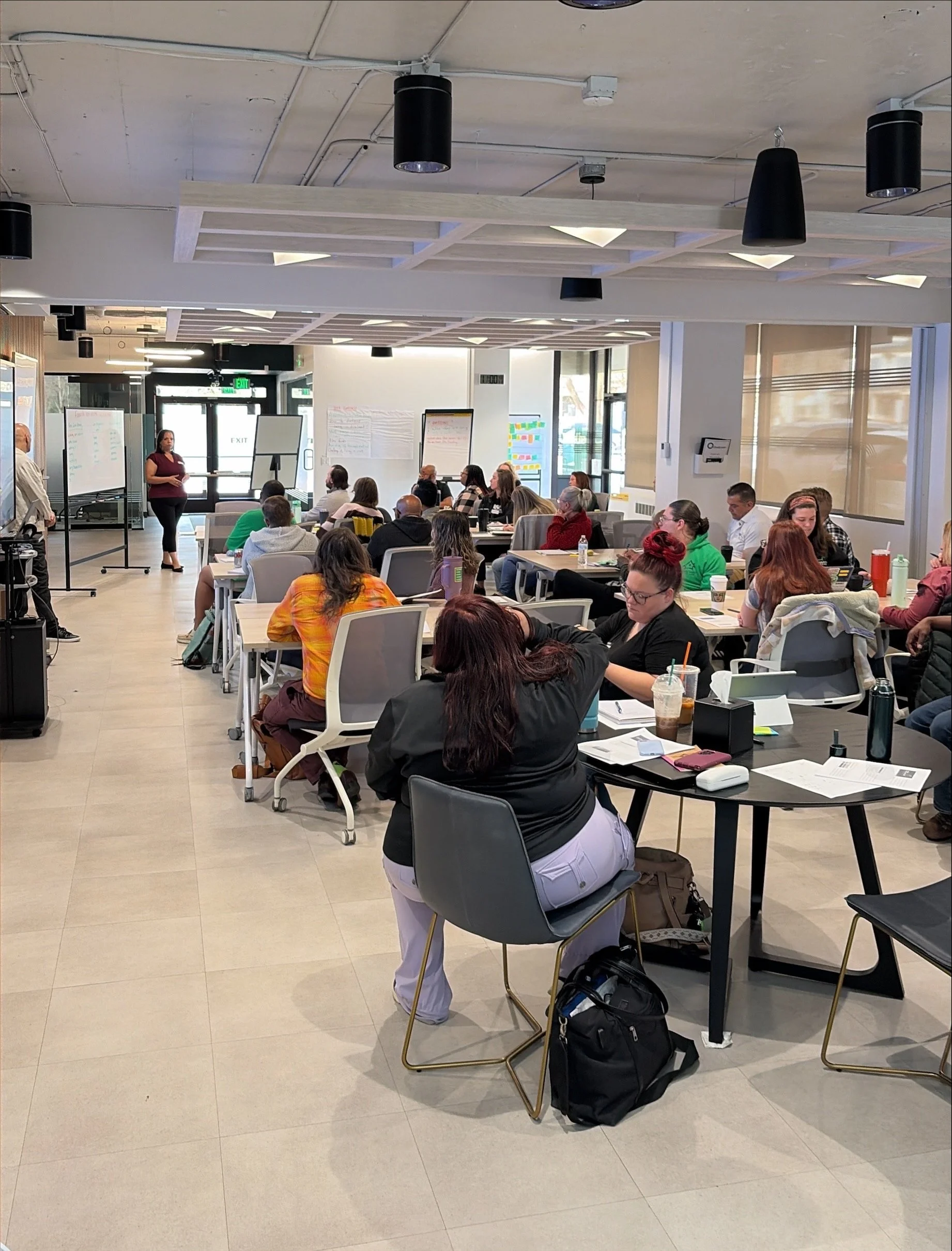 ChangeLine’s large, bright meeting space is full of people at tables watching a presentation.