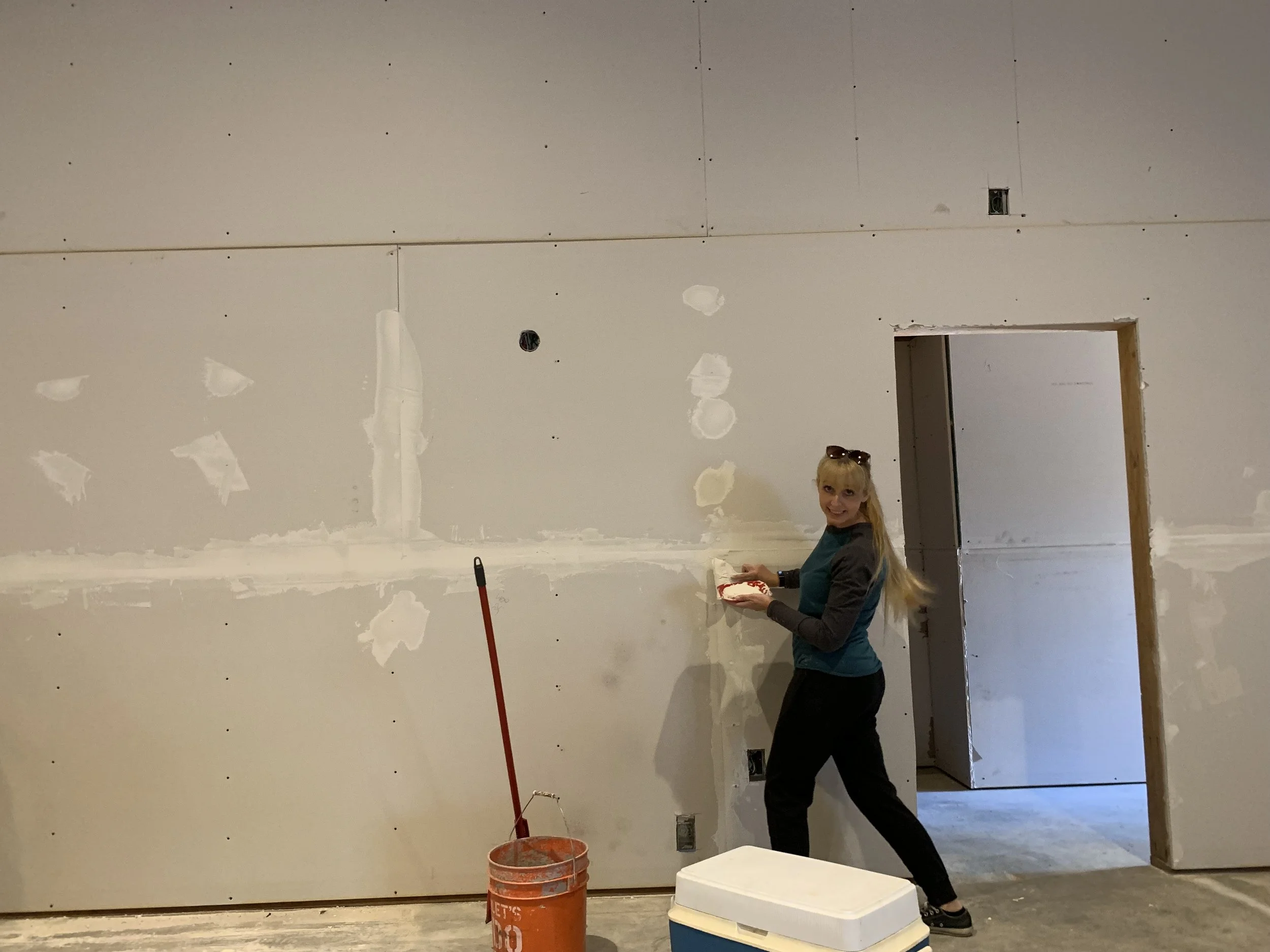 Woman applying joint compound to drywall in a construction site