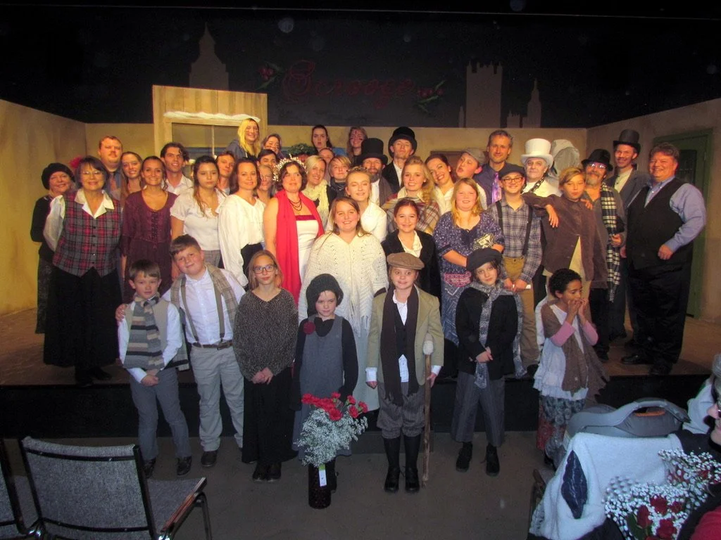 Group of actors dressed in period costumes on stage for a theatrical production.
