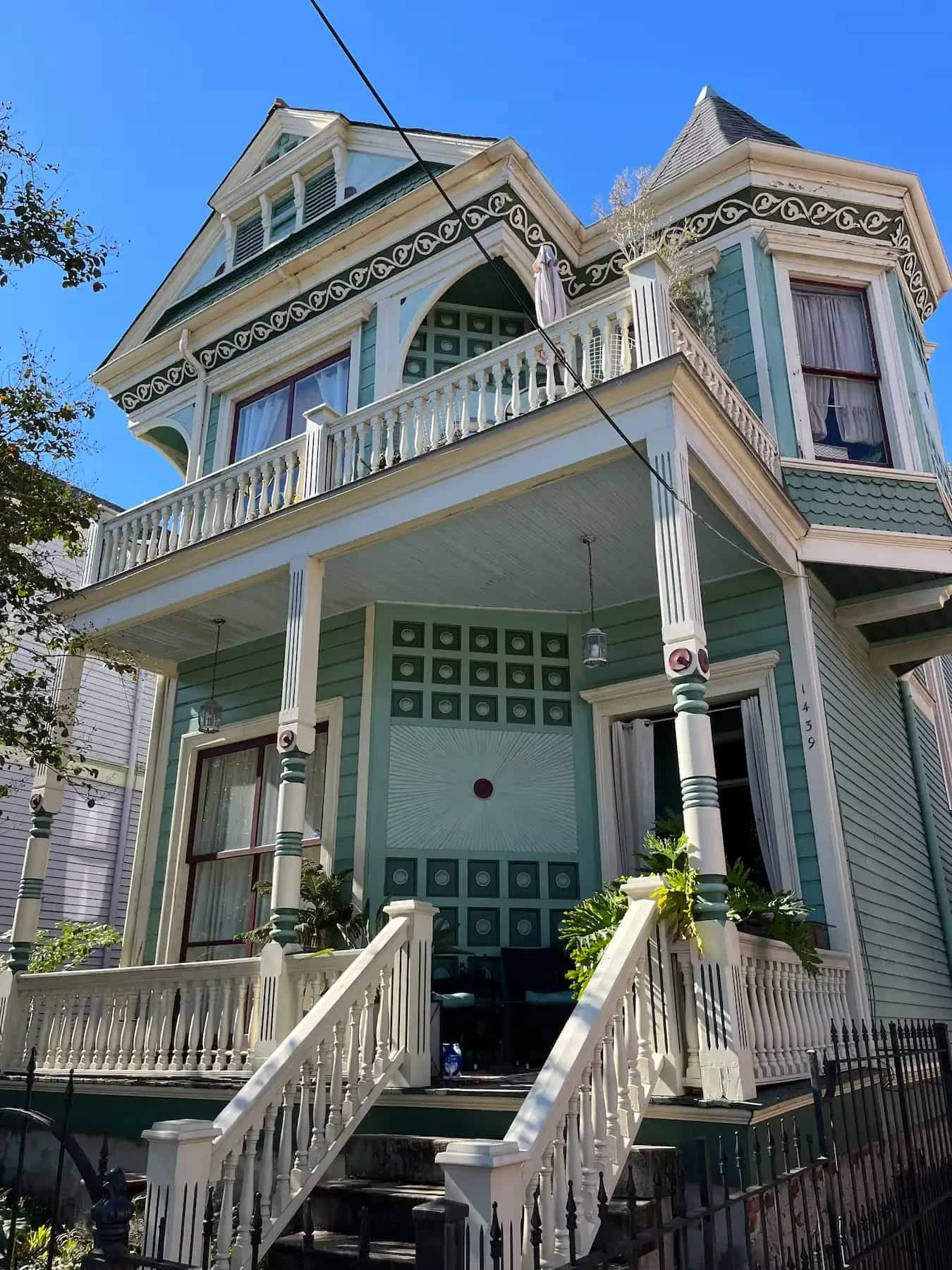 Classic teal and green Victorian house in New Orleans, Louisiana, with intricate detail and white columns.