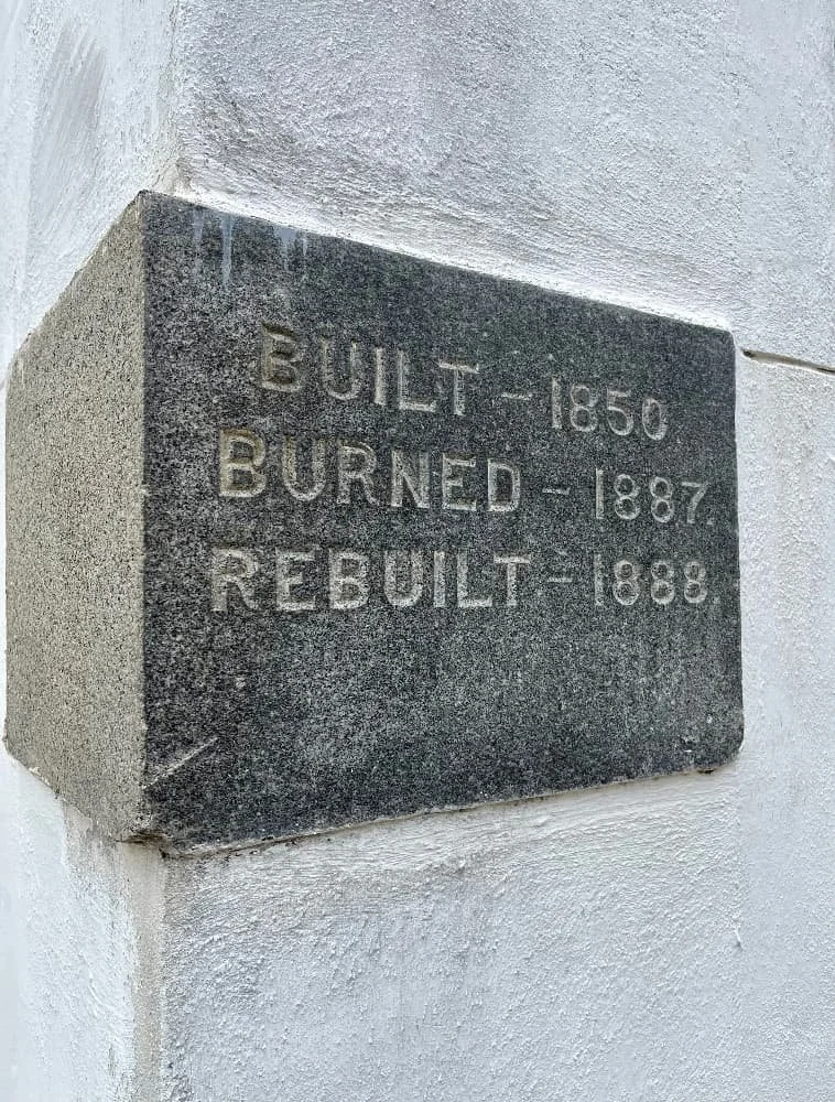 Close-up of a historic stone plaque at Felicity Church in New Orleans that reads "Built - 1850, Burned - 1887, Rebuilt - 1888.