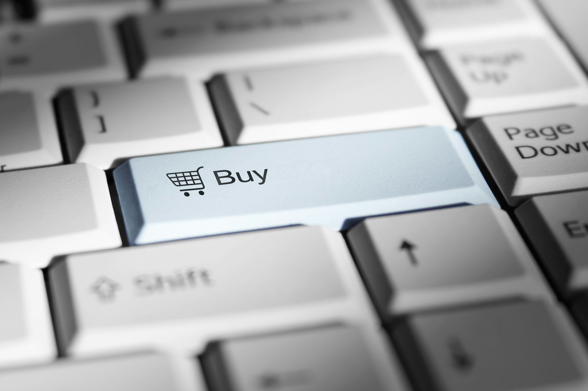 Close-up of a computer keyboard with a light blue 'Buy' key featuring a shopping cart icon.