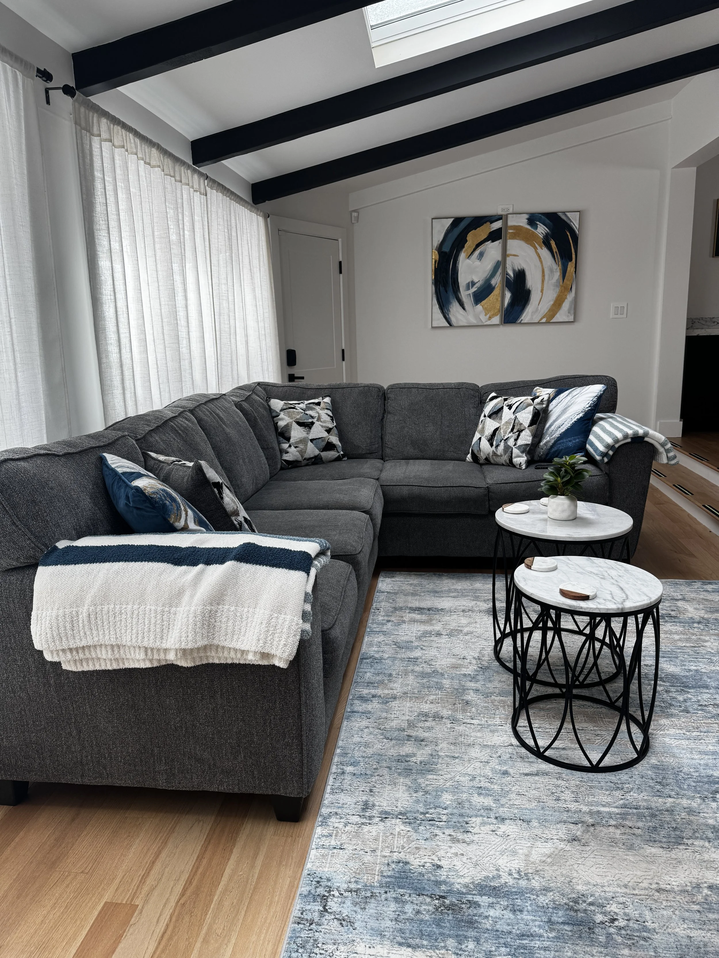 Image of cleaned charcoal colored living room, with cushions and accessories that are blue, yellow, and white colored.