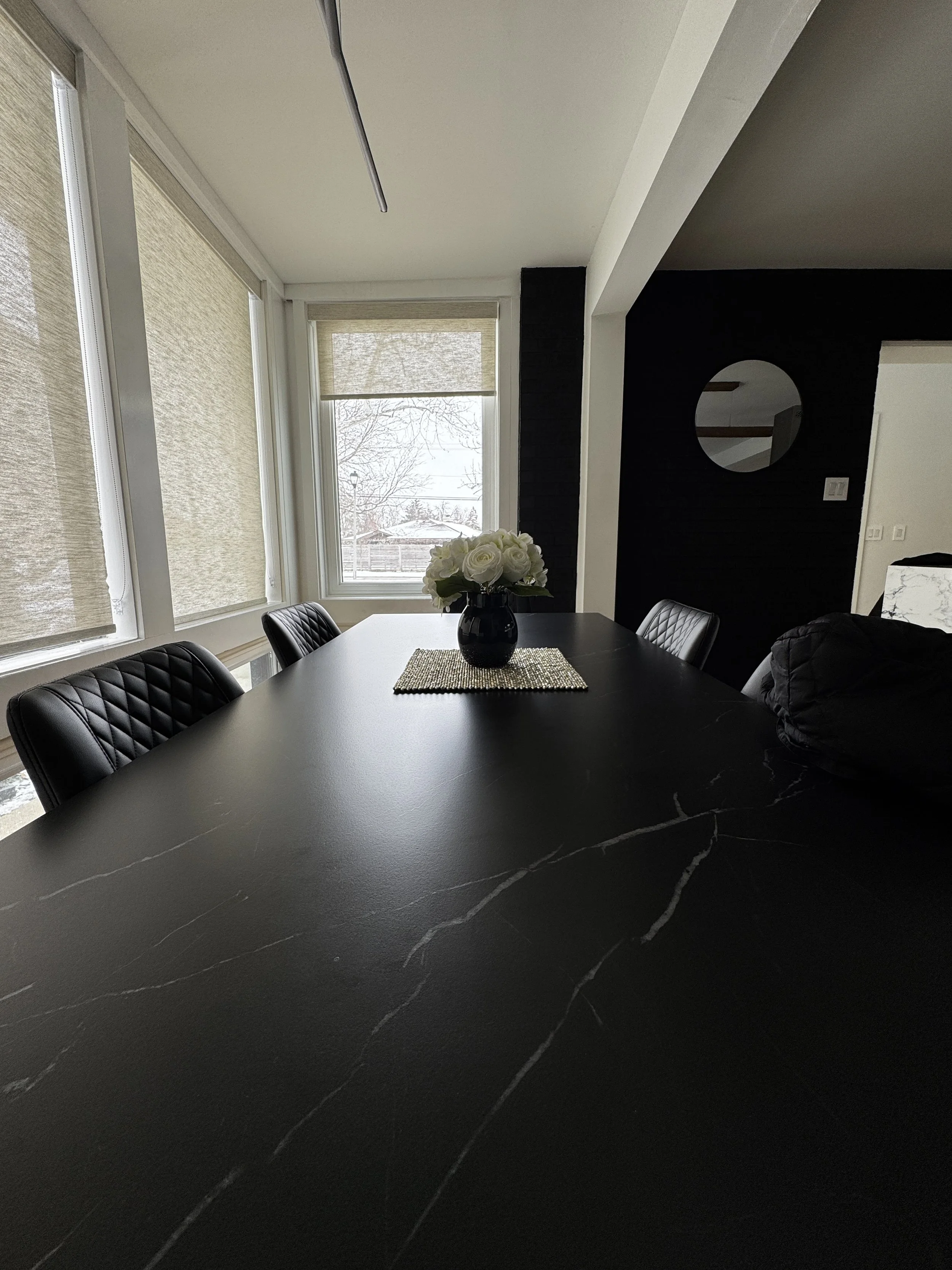black marble dinner table, light colored shades in background.