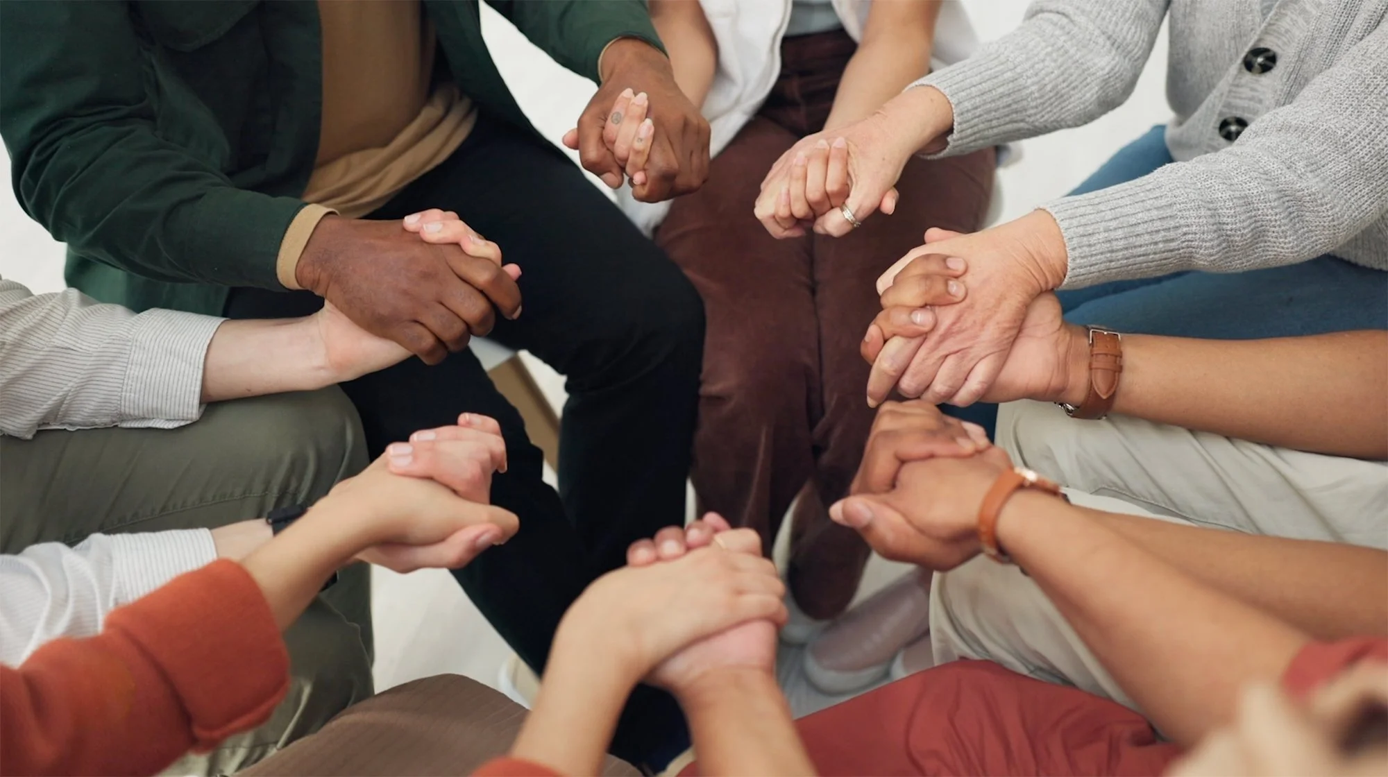 Group of diverse people's hands holding each other in unity.