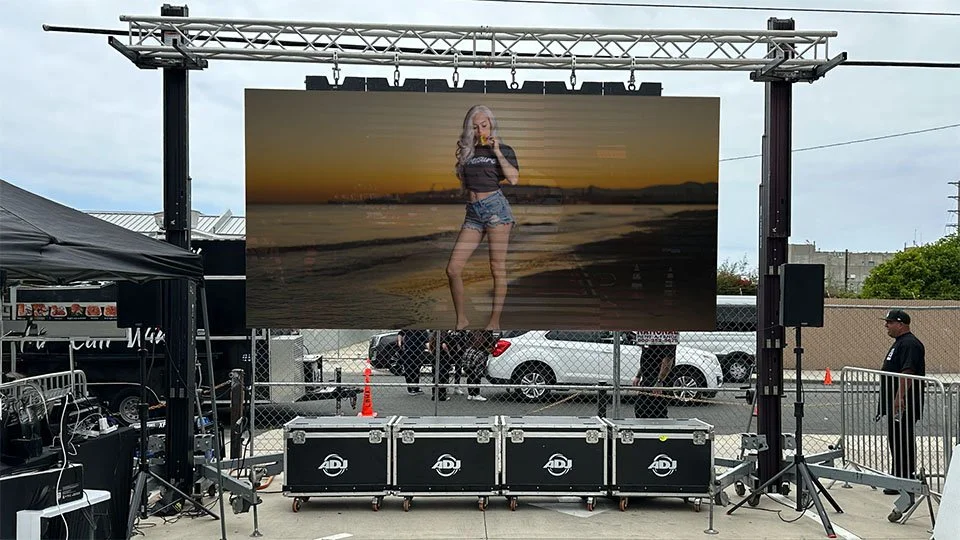 ProWall LED Wall Rental outdoor screen displaying a woman taking a selfie at the beach during sunset.