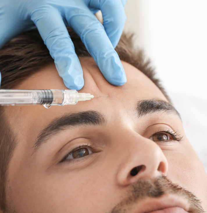 A person receiving a Botox injection in the forehead from a healthcare professional wearing blue gloves.