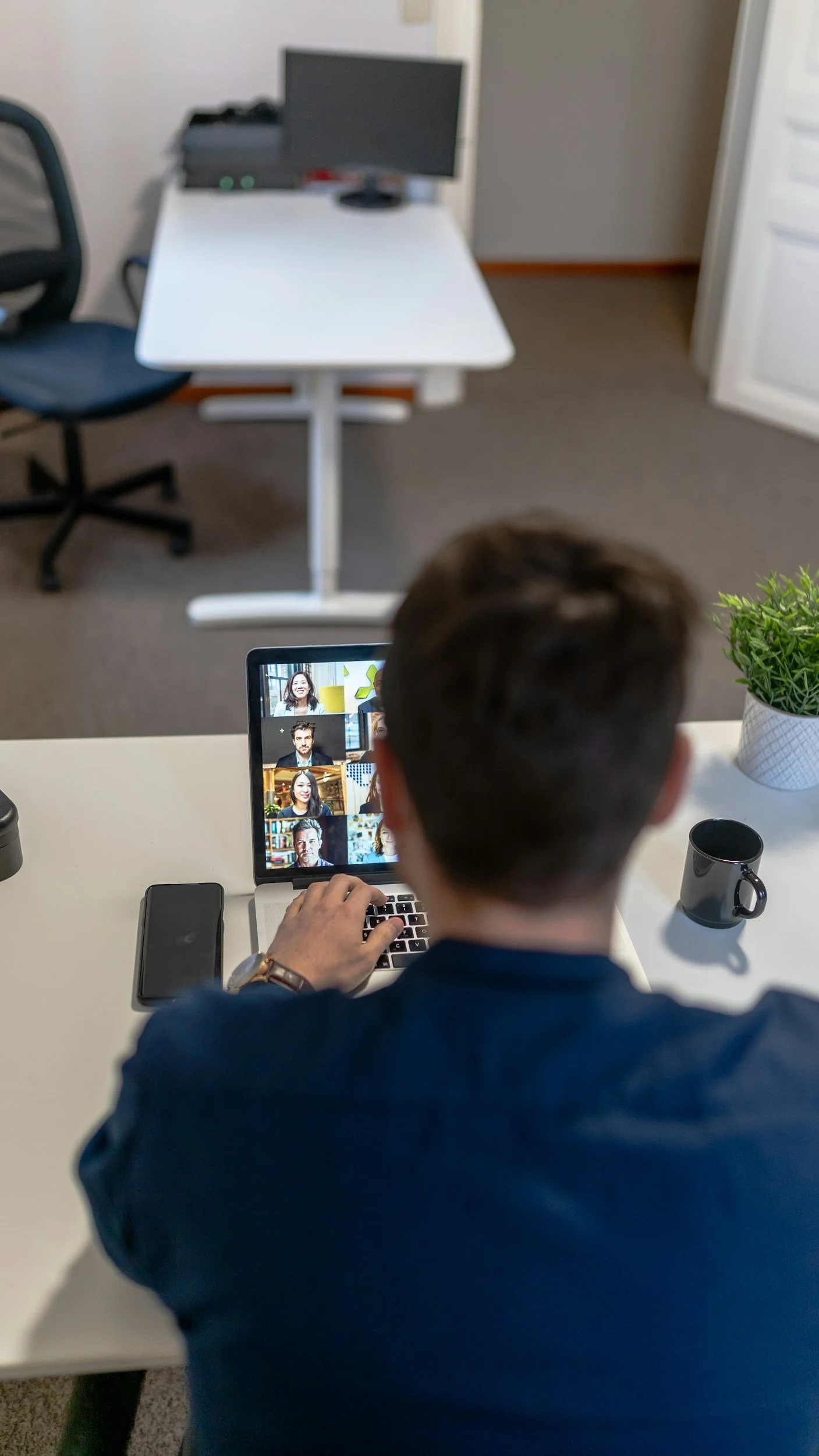 Person attending a video conference on a laptop at a home office desk