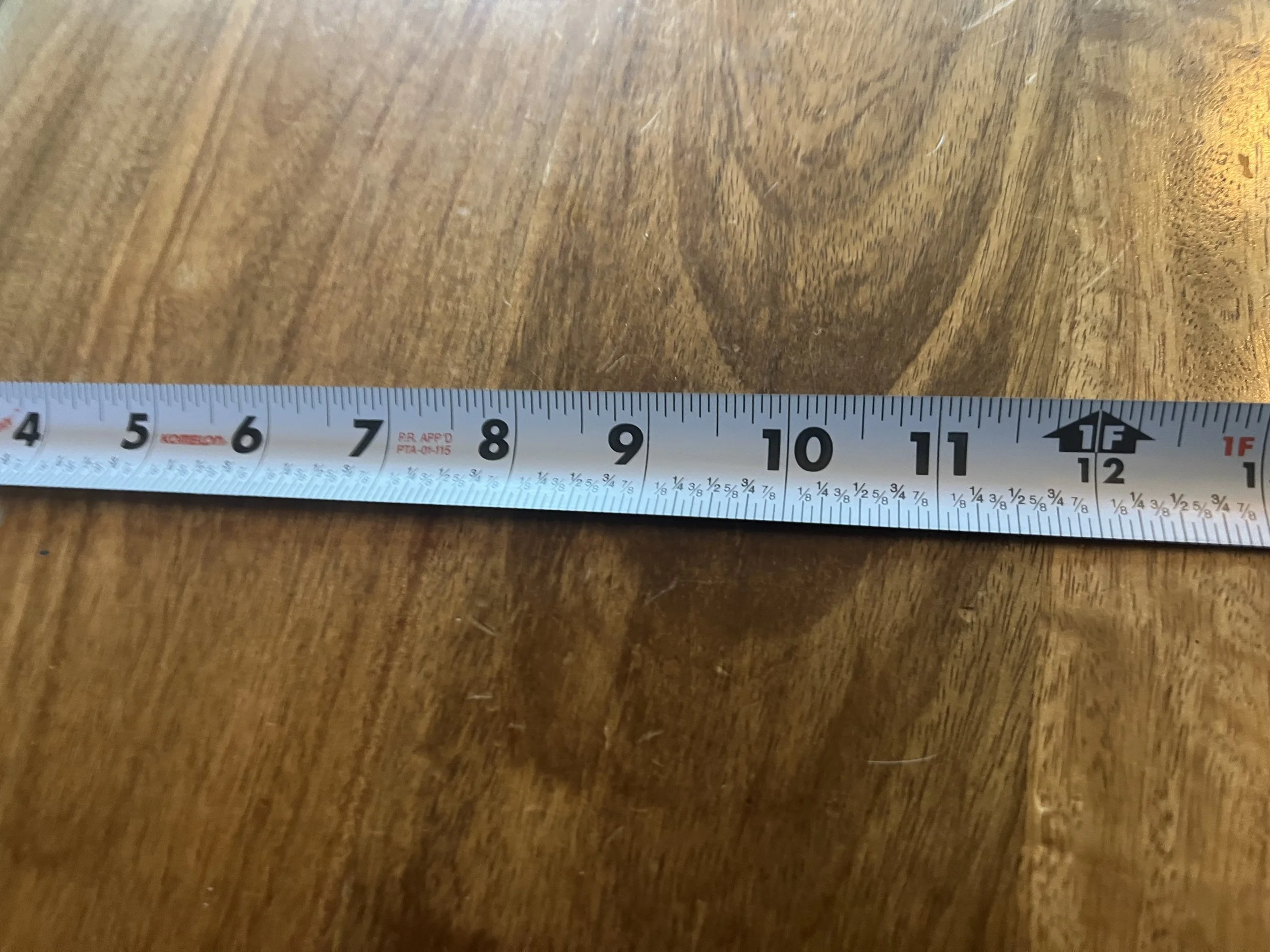 White measuring tape measuring the width of a wooden bench.