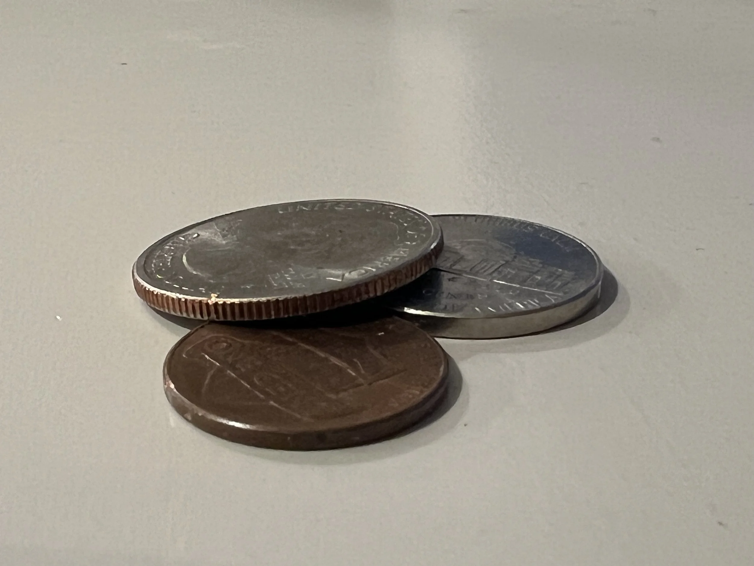 A quarter, nickel, and penny on a white surface.