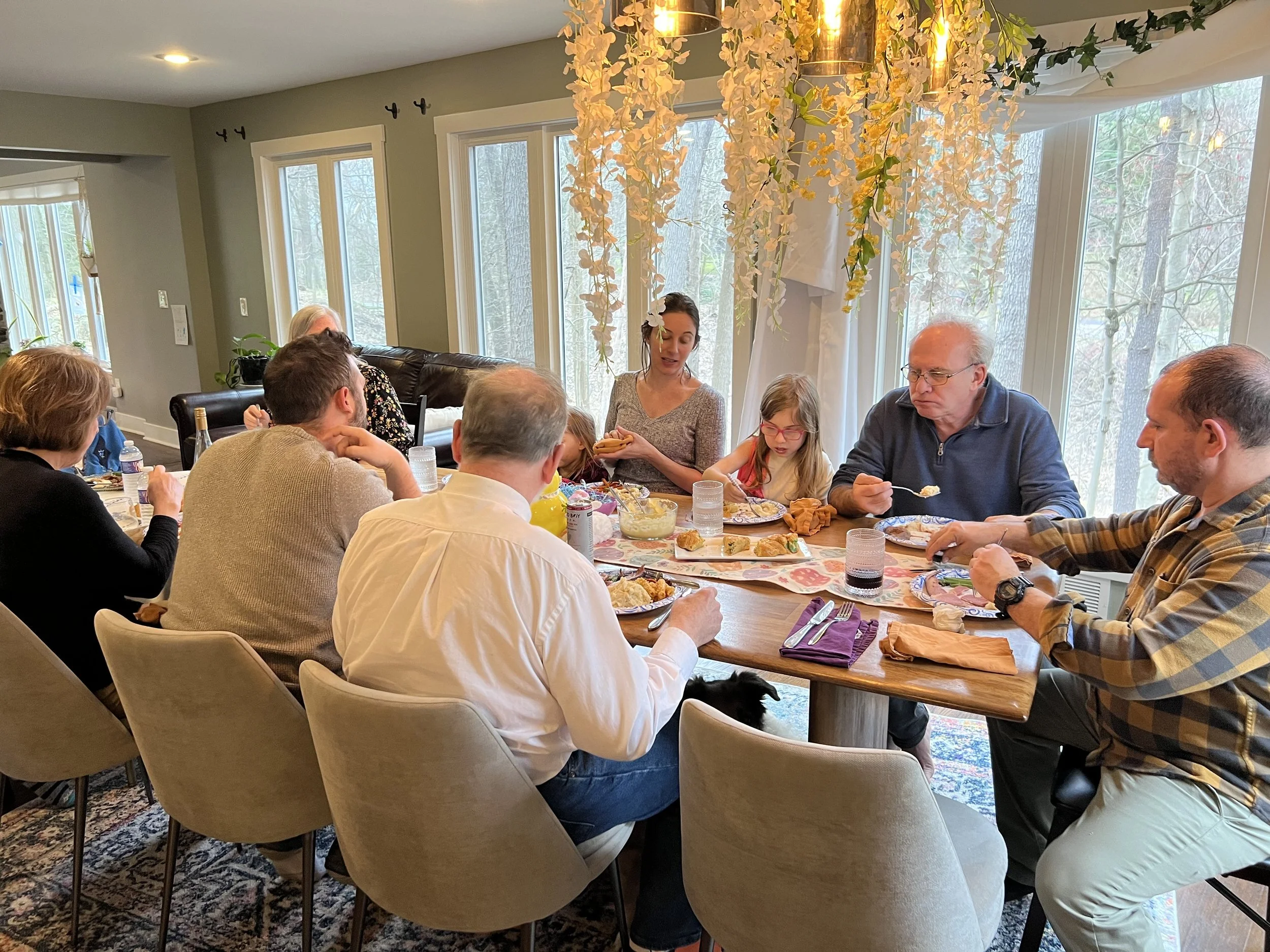 Group of people sitting around dining room tables eating and talking to one another.