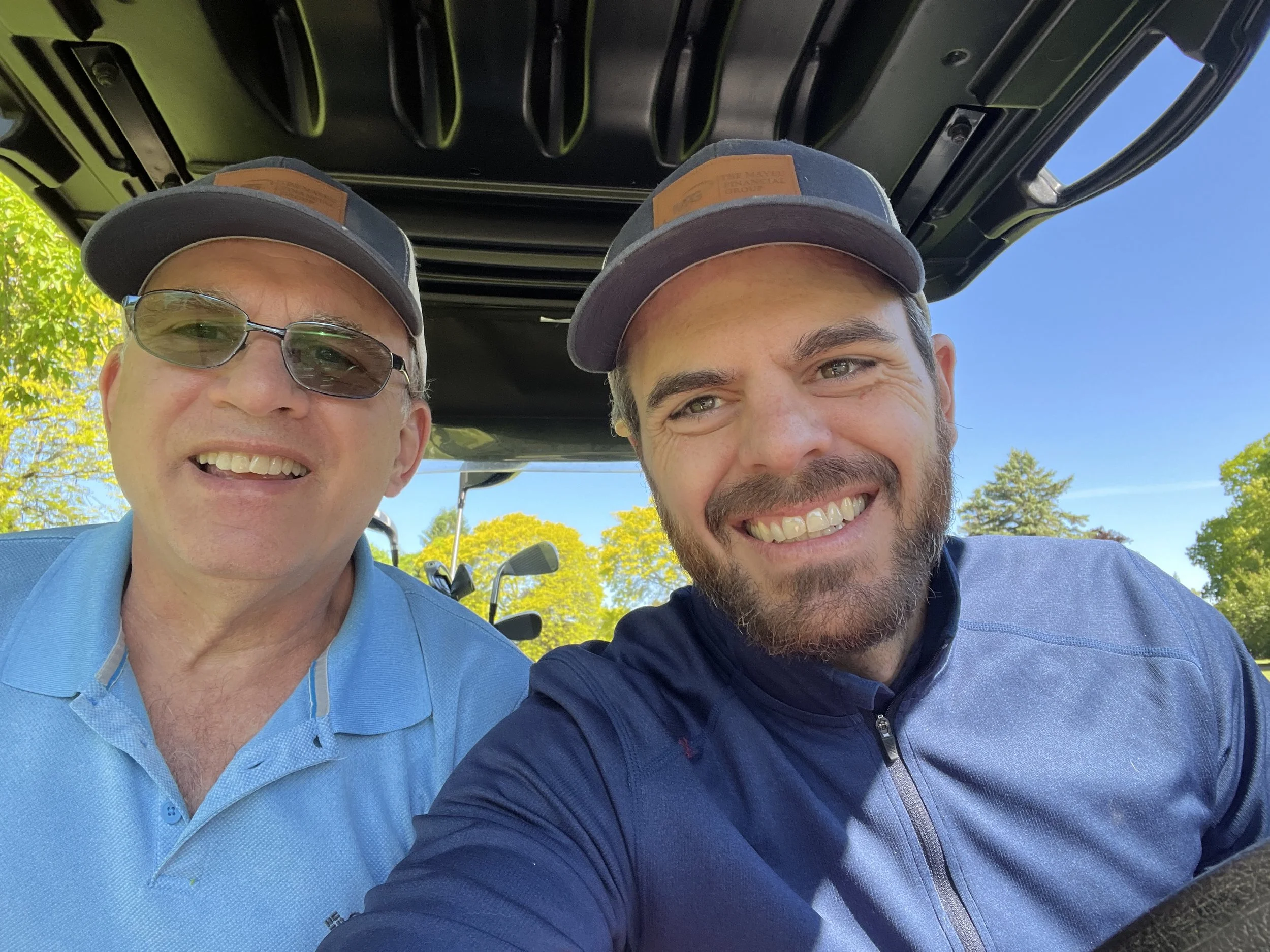 Two caucasian males in a golf cart.