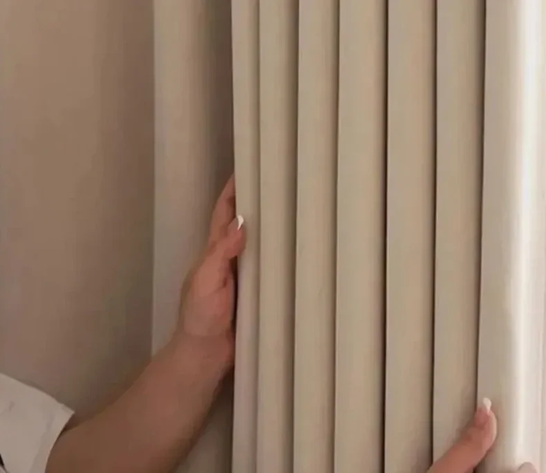 A person adjusting beige vertical blinds covering a window.